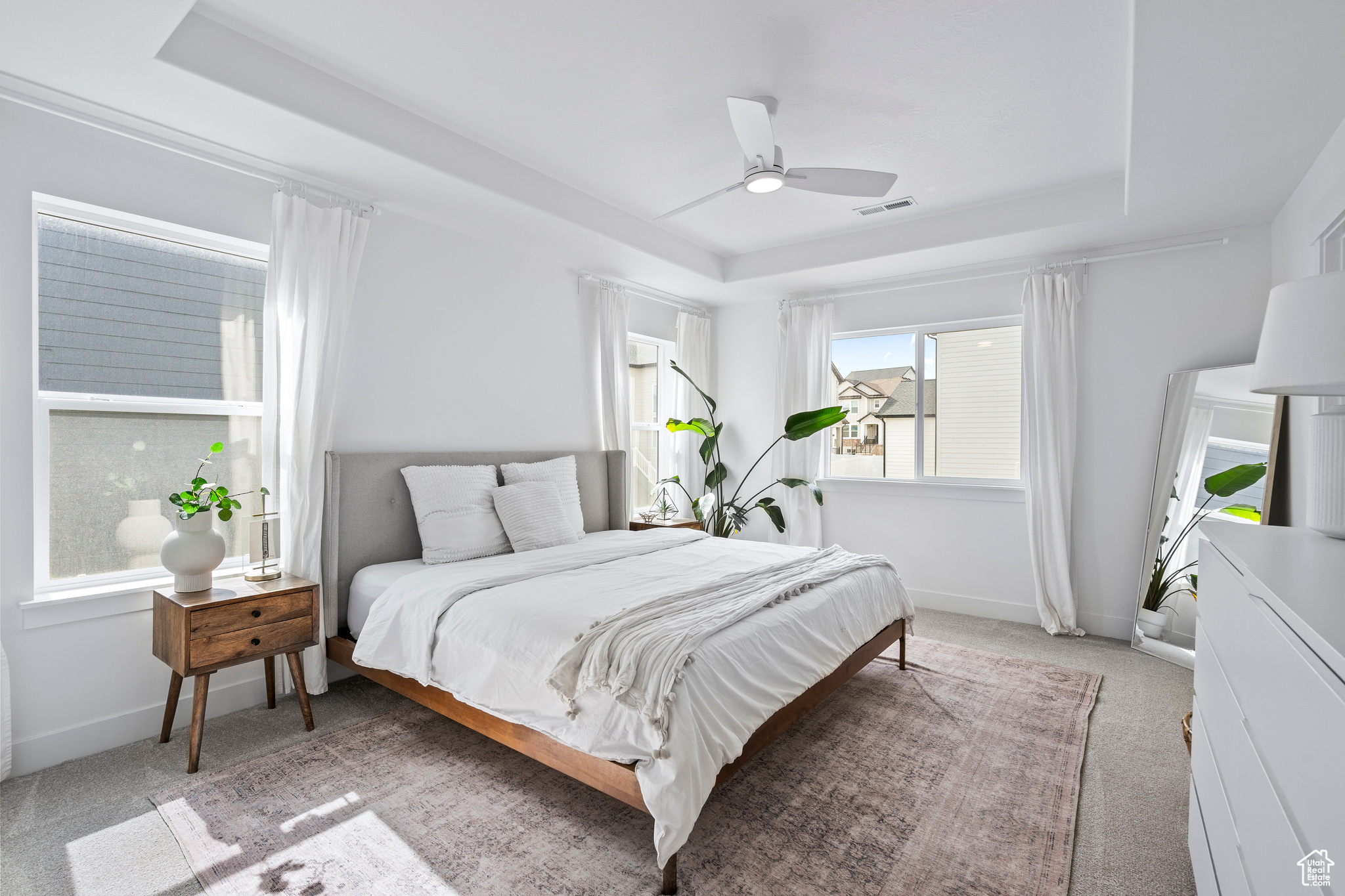Bedroom with a tray ceiling, baseboards, light colored carpet, and visible vents