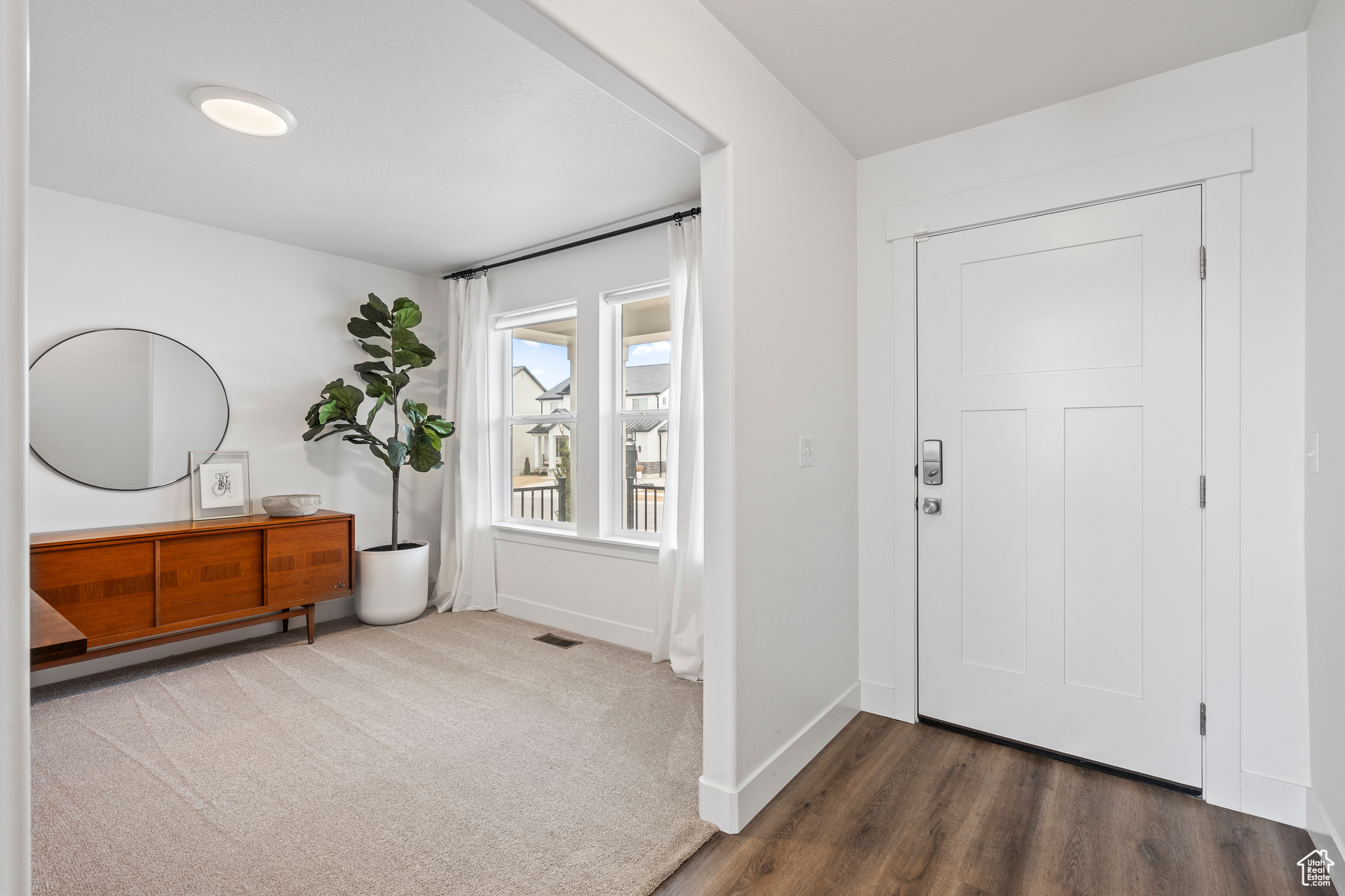 Carpeted entrance foyer with visible vents and baseboards