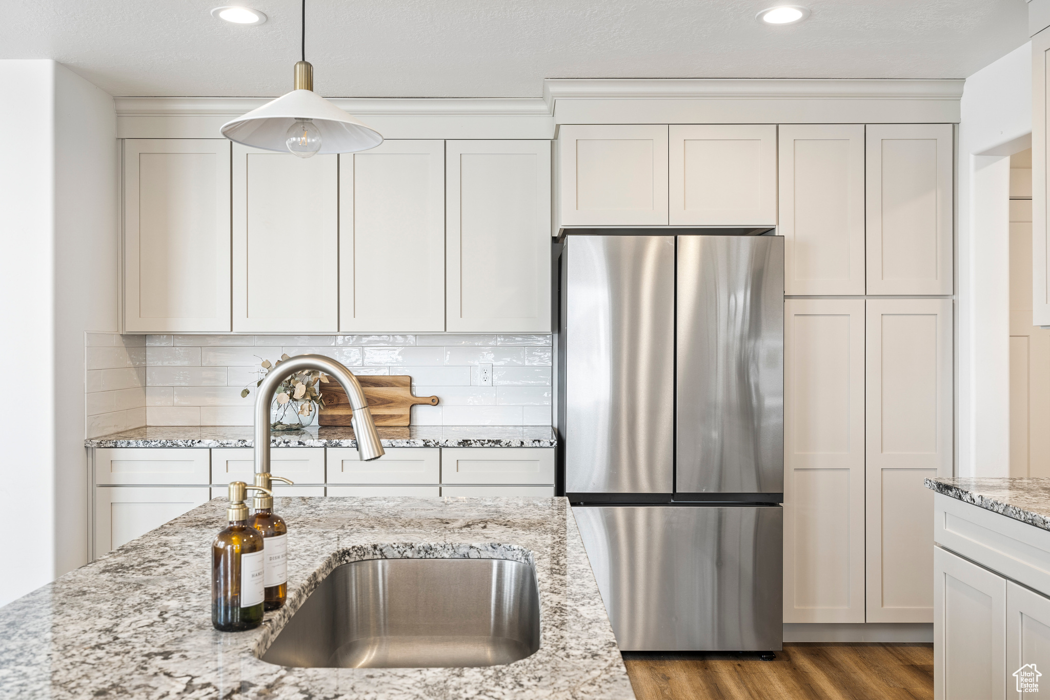 Kitchen featuring wood finished floors, tasteful backsplash, freestanding refrigerator, and a sink