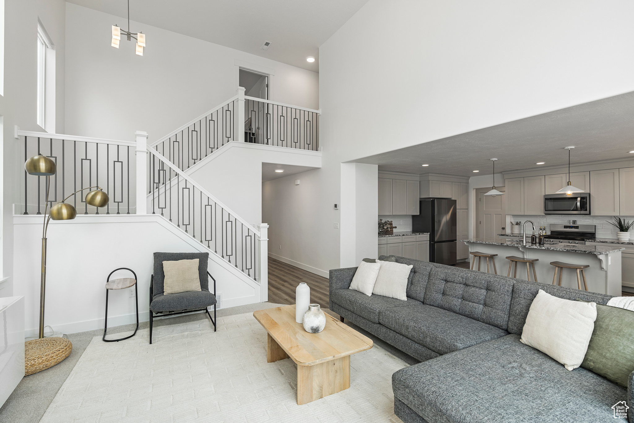 Living area featuring light wood-type flooring, recessed lighting, stairway, a high ceiling, and baseboards