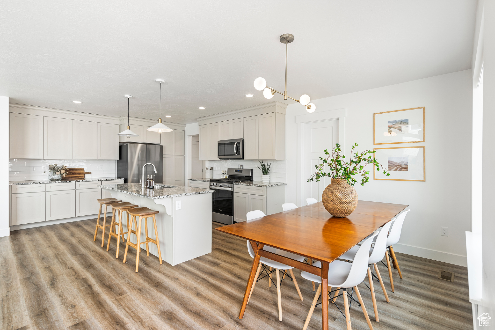Kitchen with a kitchen bar, backsplash, appliances with stainless steel finishes, and a center island with sink