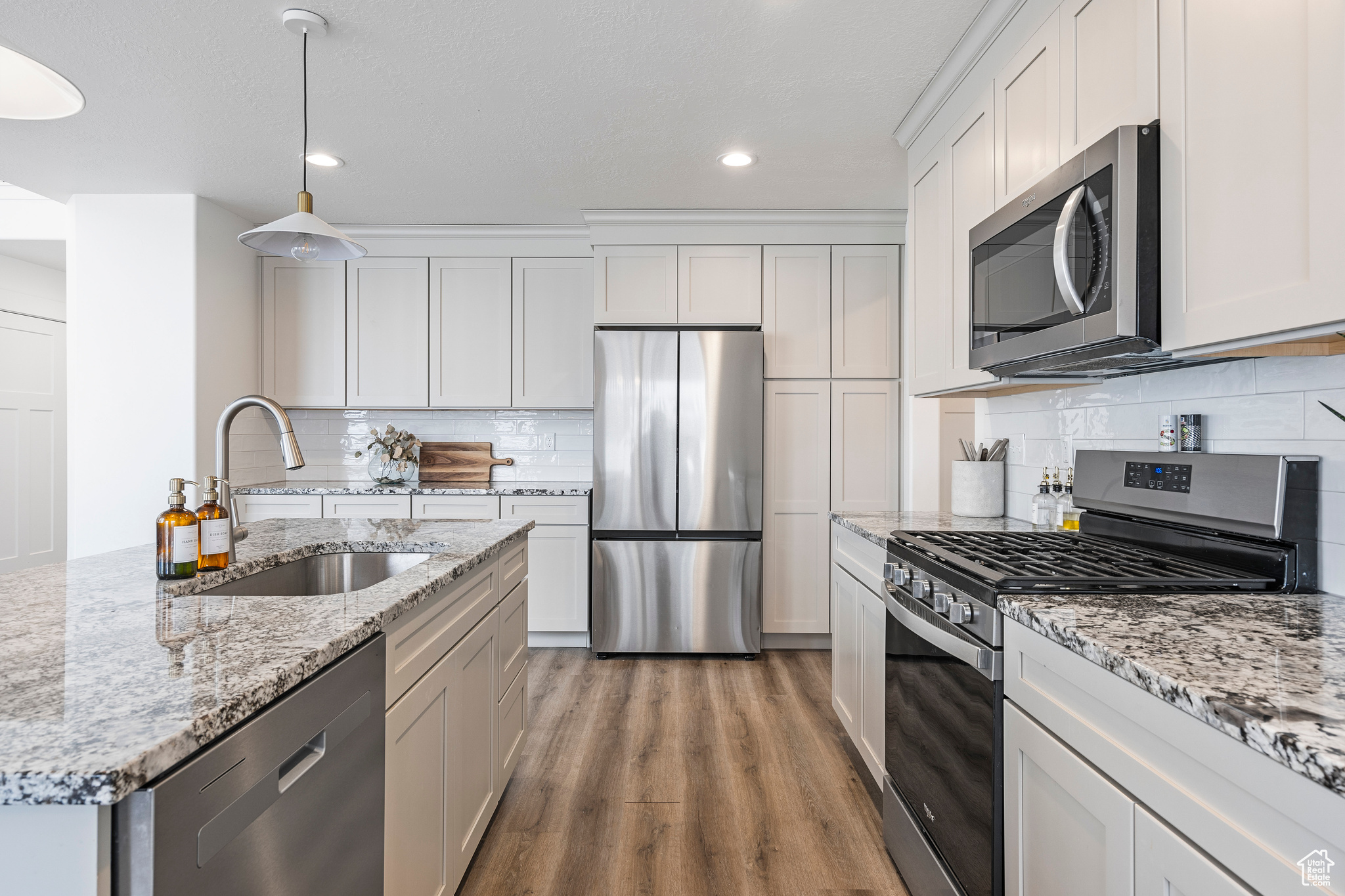 Kitchen featuring a sink, decorative backsplash, appliances with stainless steel finishes, and wood finished floors