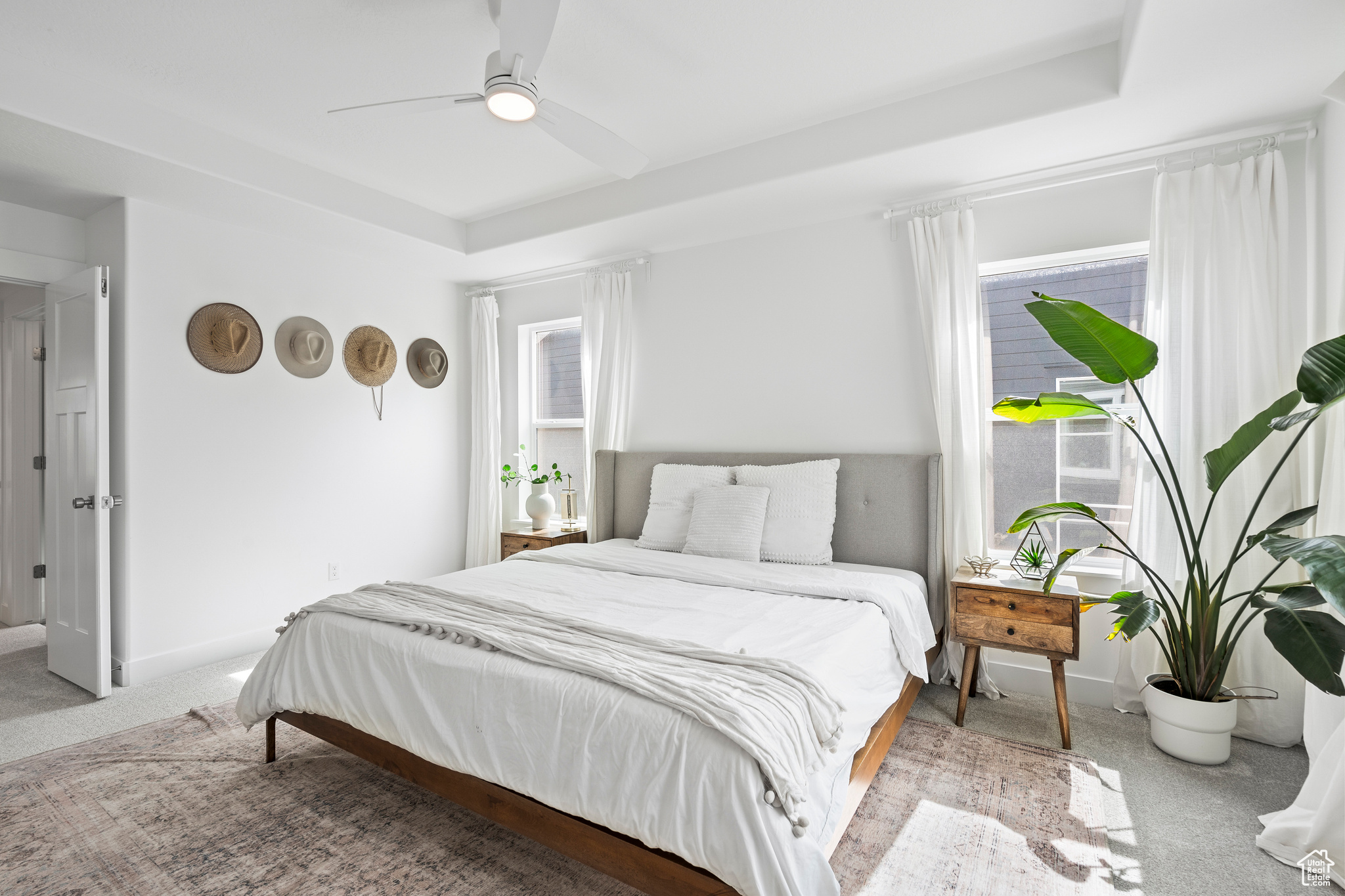Bedroom featuring multiple windows, baseboards, a tray ceiling, and carpet floors