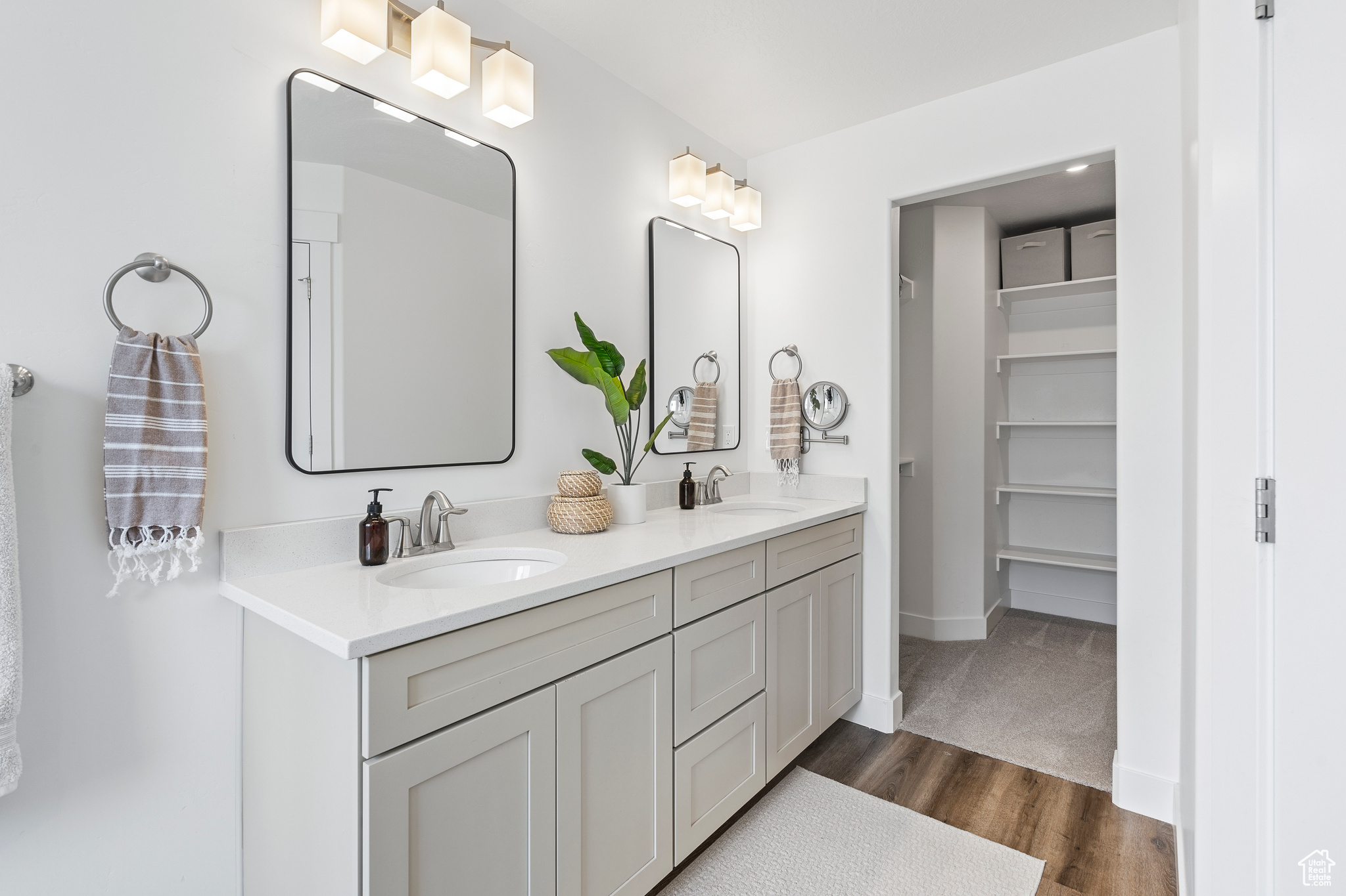 Bathroom featuring a sink, baseboards, wood finished floors, and double vanity