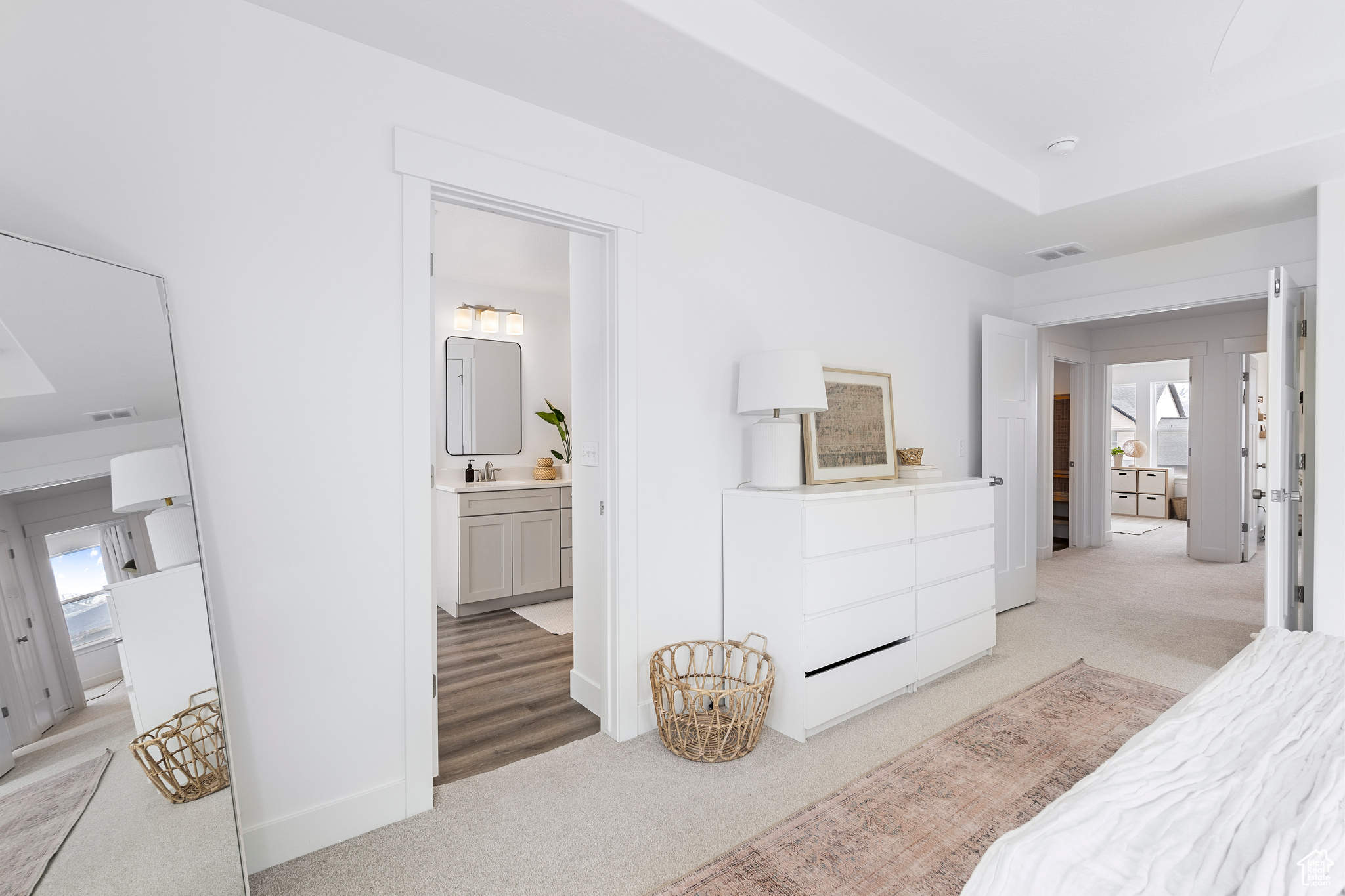 Bedroom with visible vents, light carpet, baseboards, and ensuite bathroom