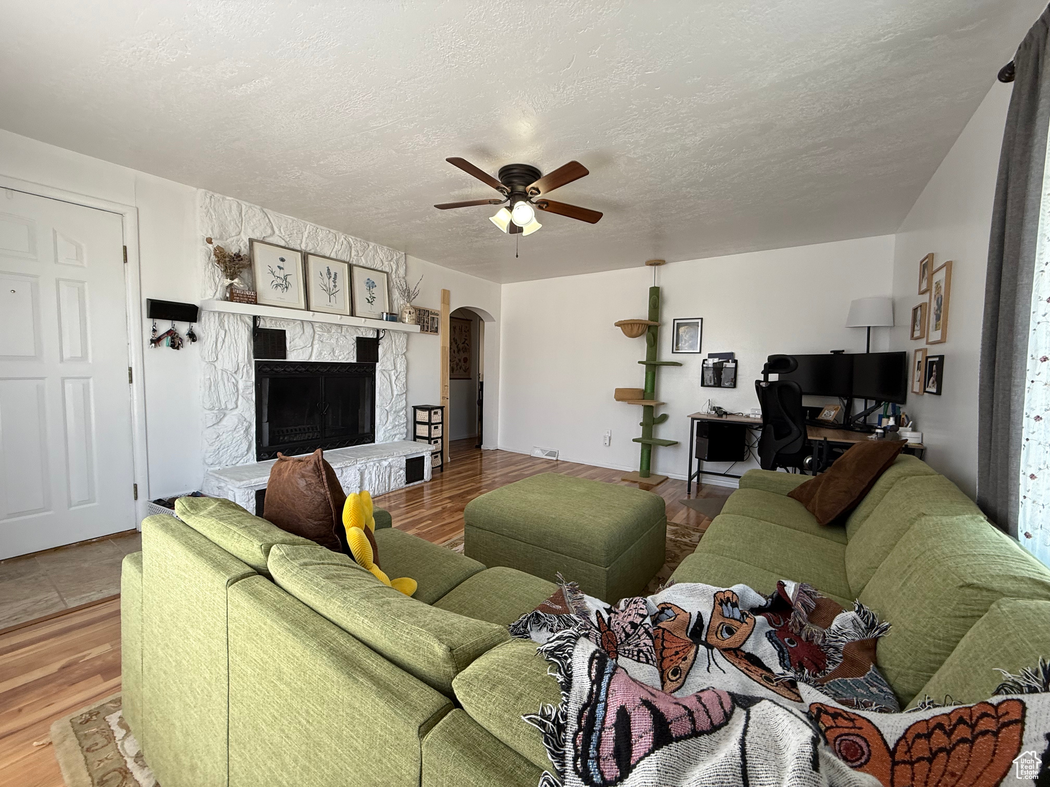 Living room featuring arched walkways, a ceiling fan, wood finished floors, and a fireplace