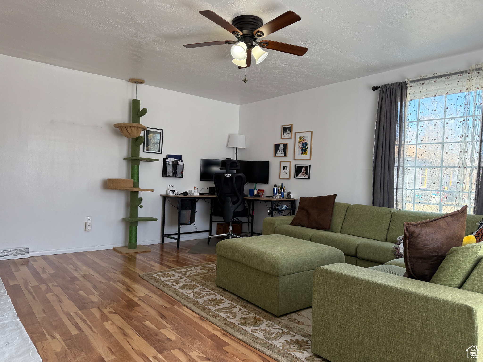 Living room with visible vents,  wood finished floors, baseboards, and ceiling fan