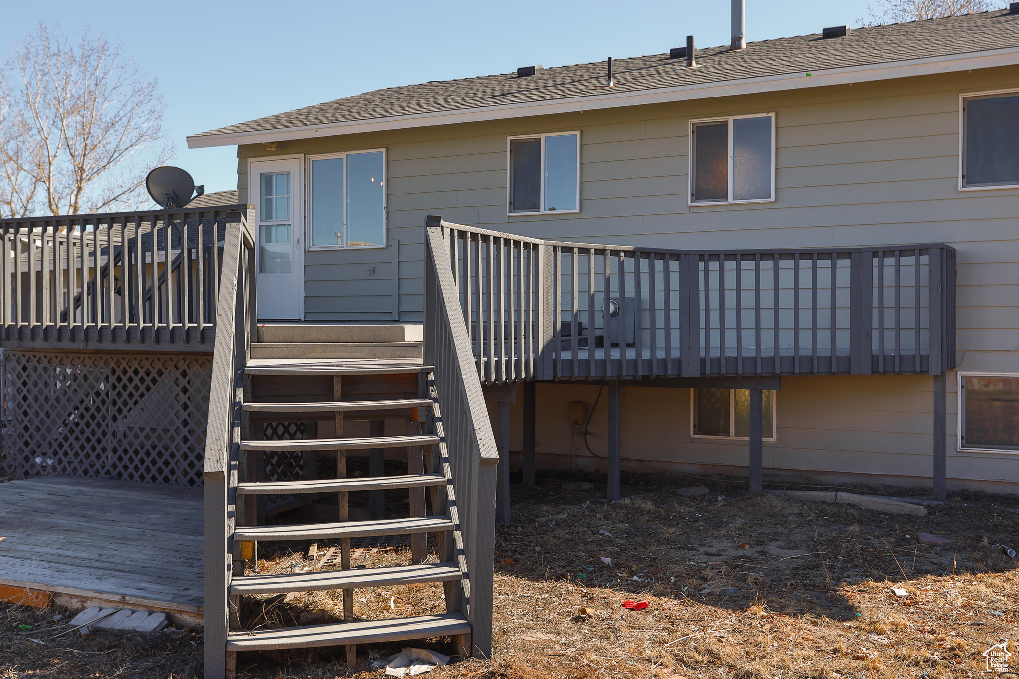 Rear view of property with stairway, a deck, and a shingled roof