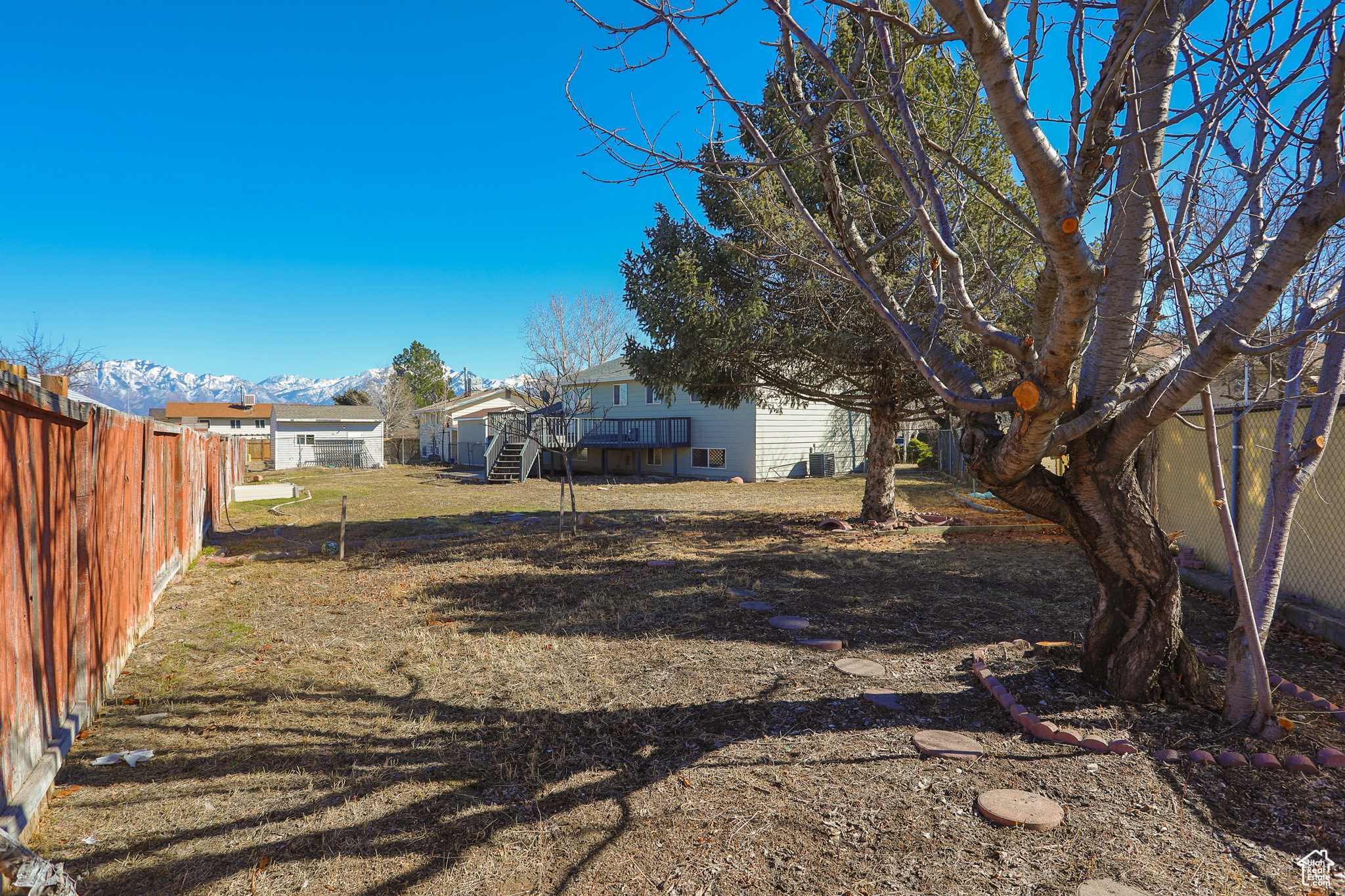 View of yard featuring a deck with mountain view, a fenced backyard, and stairs