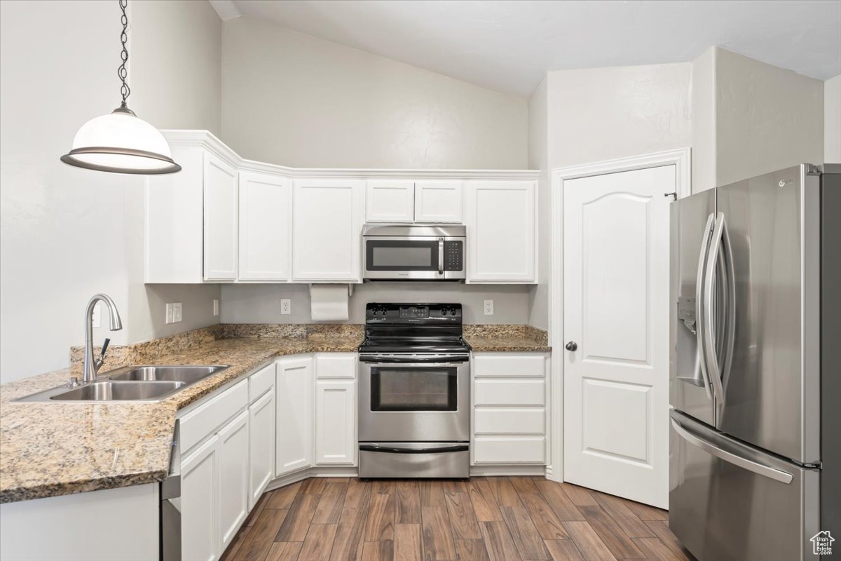 Kitchen with dark wood finished floors, white cabinetry, stainless steel appliances, and a sink