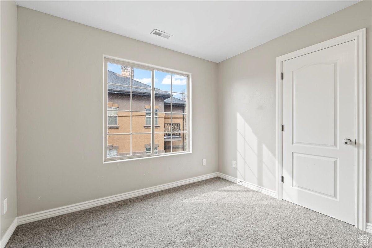 Carpeted empty room with visible vents and baseboards