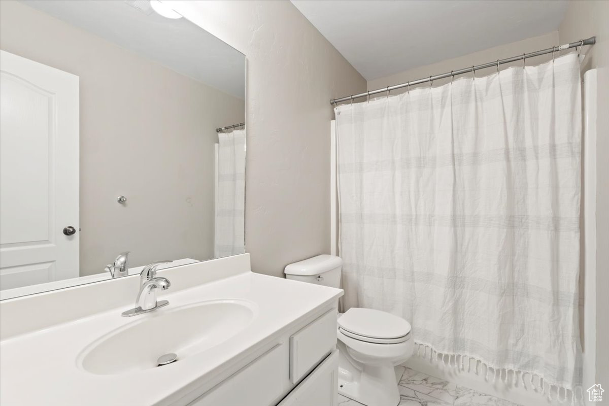 Full bath with marble finish floor, toilet, vanity, and a shower with curtain