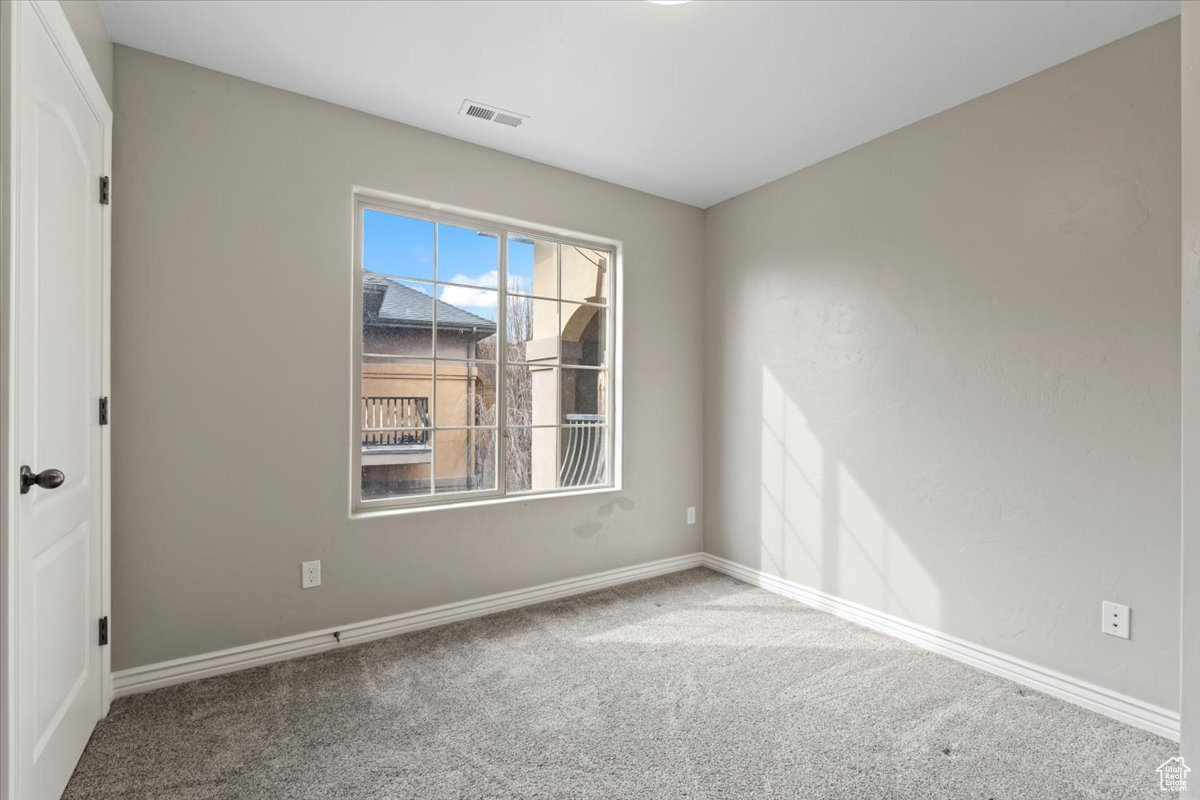 Carpeted spare room featuring visible vents and baseboards