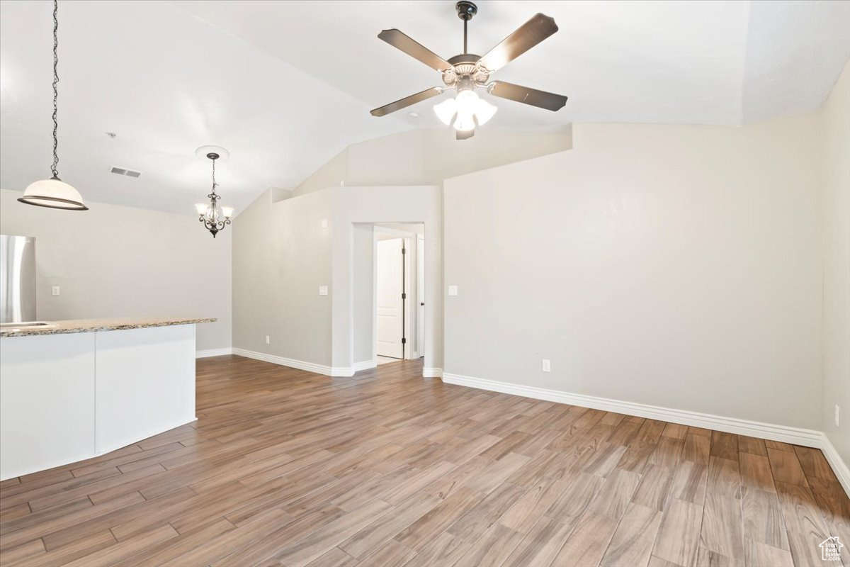 Unfurnished living room with lofted ceiling, baseboards, visible vents, and light wood finished floors