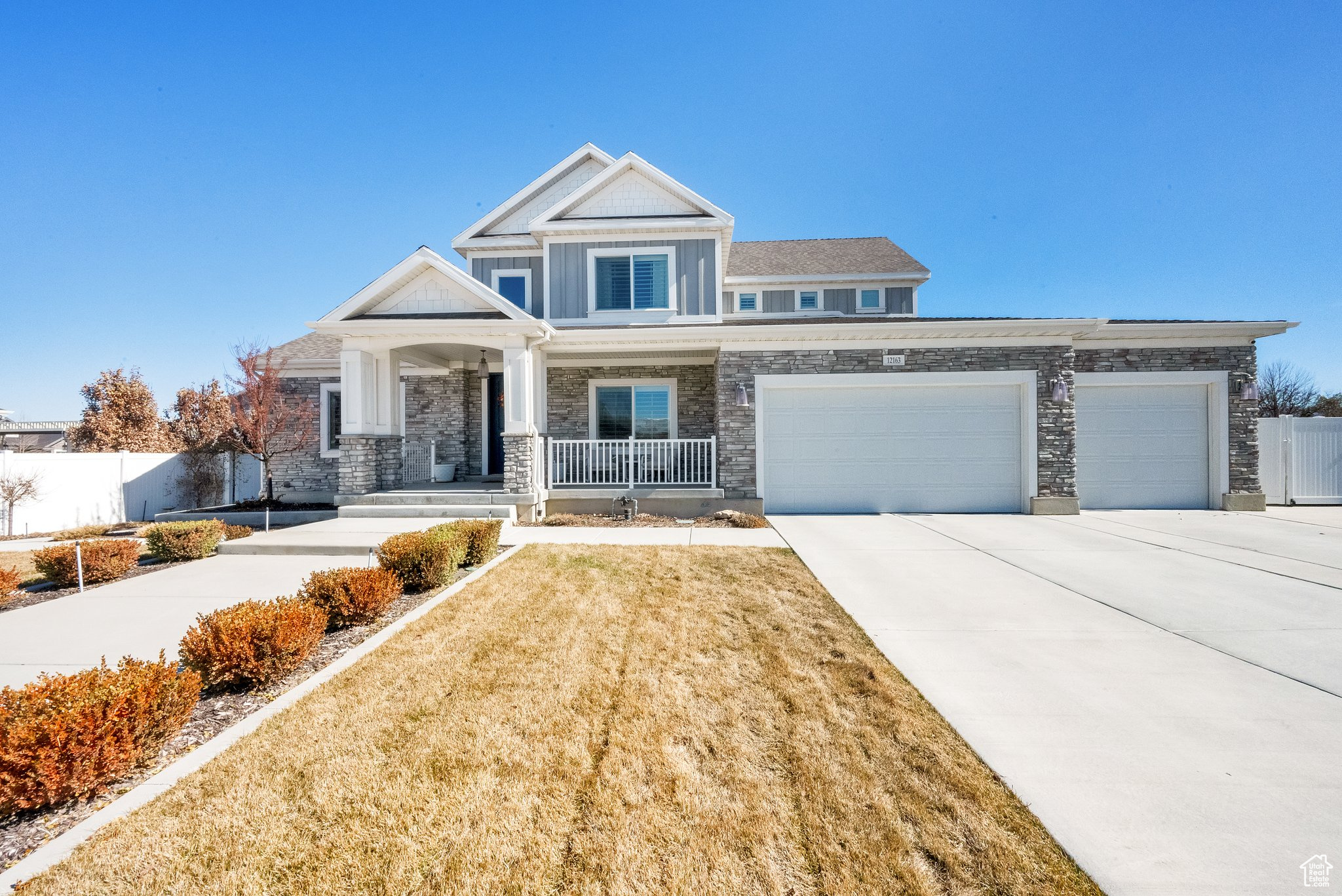 Craftsman-style home featuring a porch, fence, board and batten siding, concrete driveway, and an attached garage