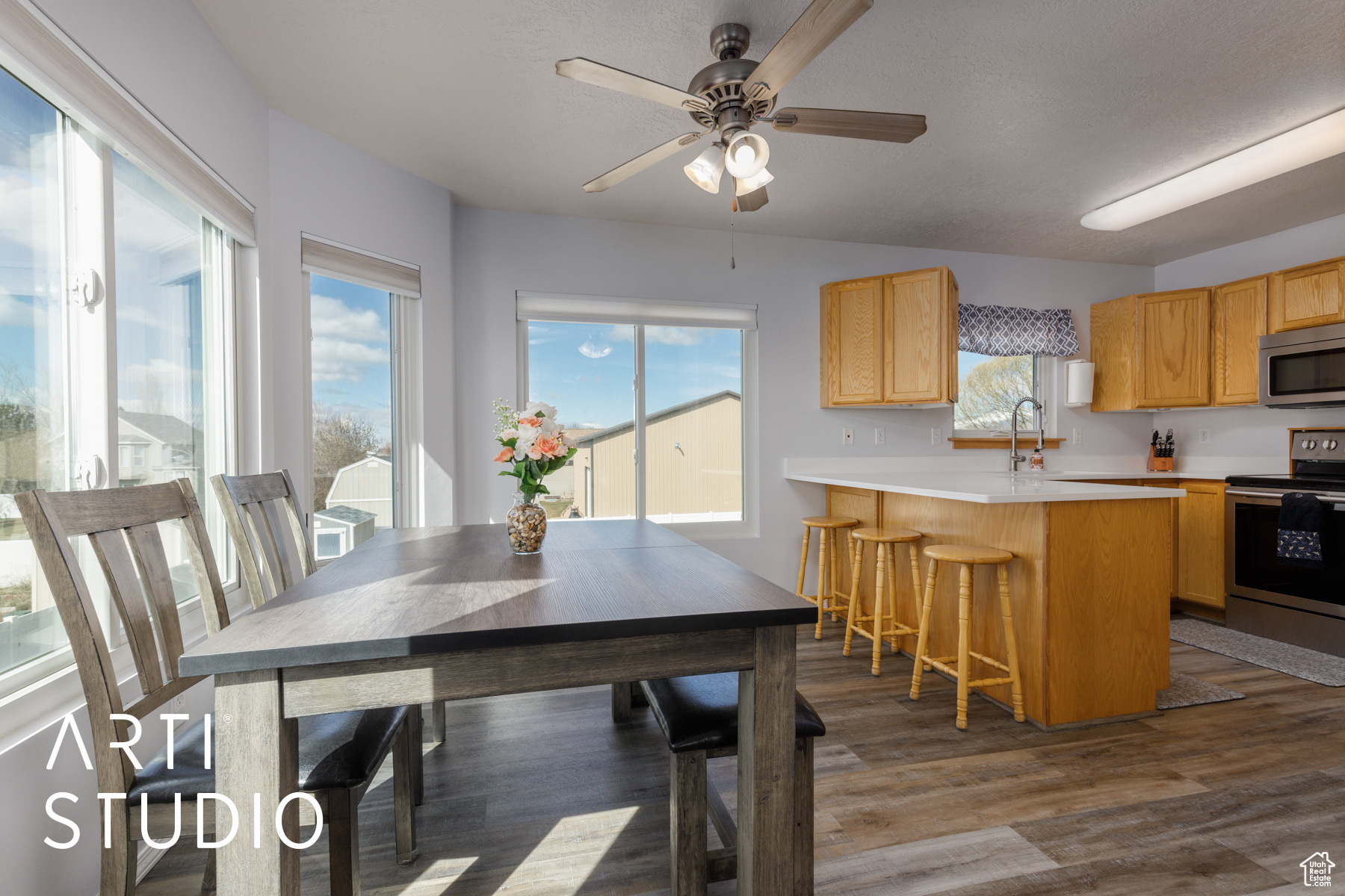 Dining room with a wealth of natural light, ceiling fan, and dark wood-style flooring