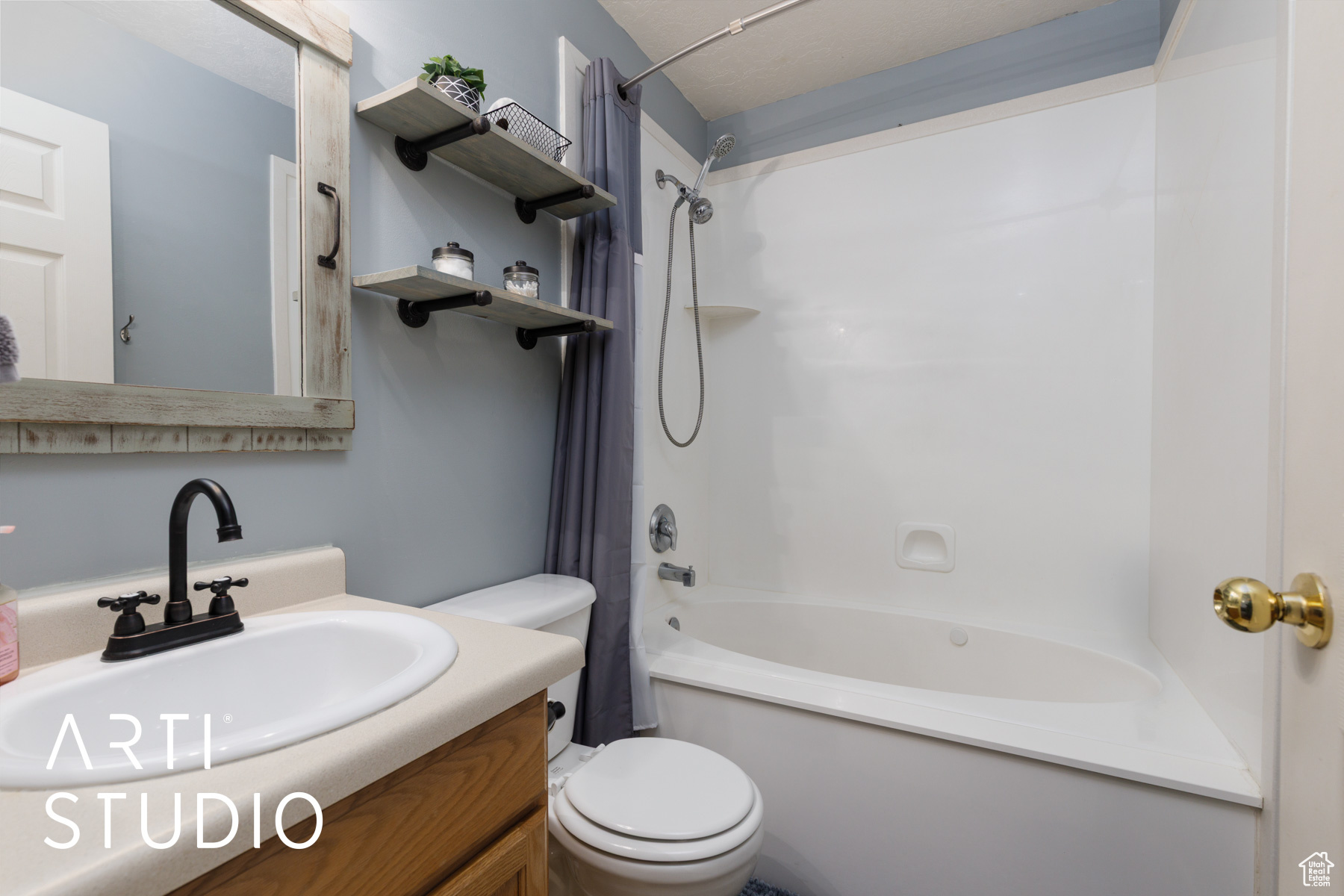 Full bathroom featuring vanity, shower / bath combination with curtain, and toilet
