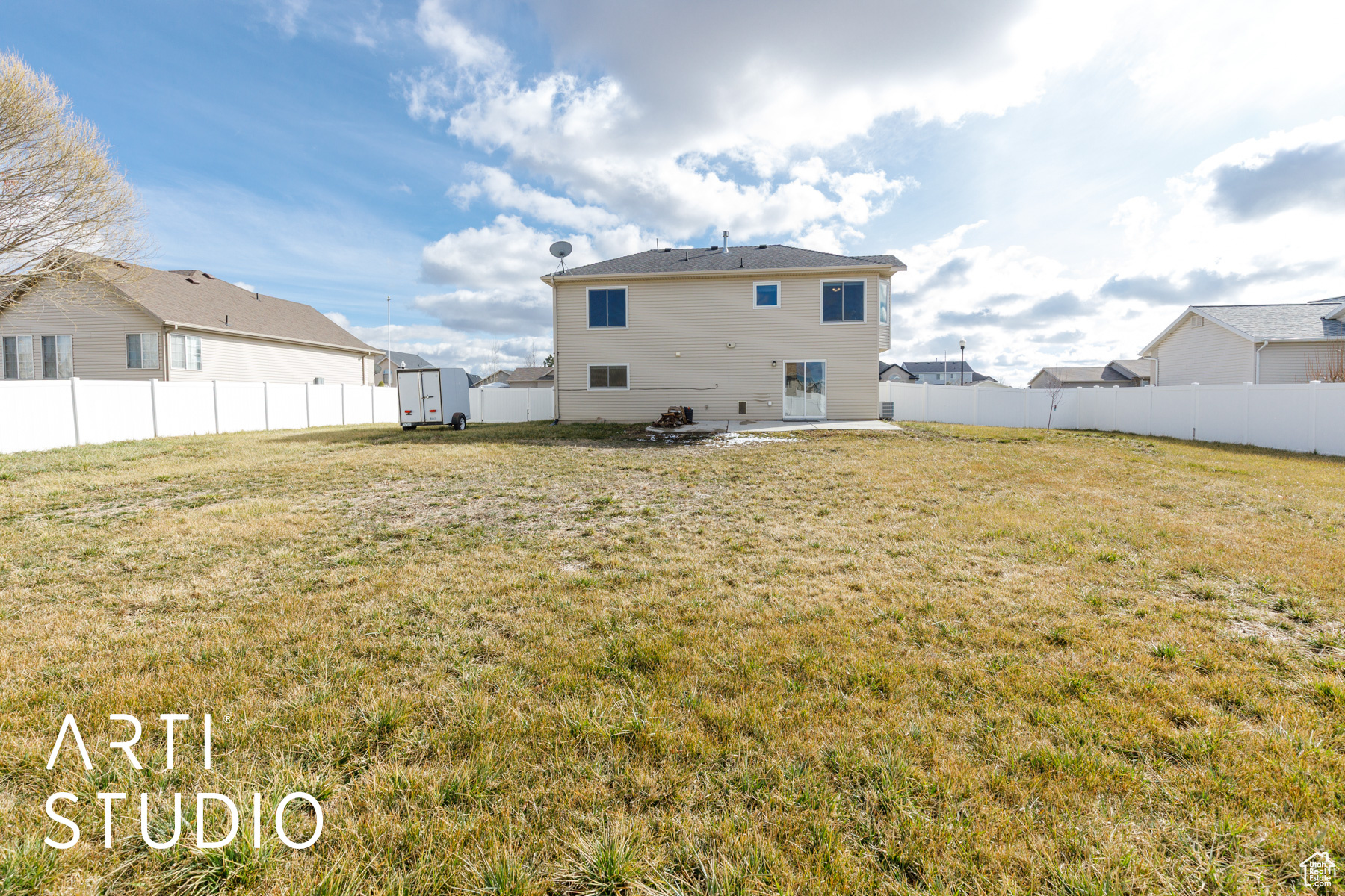 Rear view of house with a patio, a fenced backyard, an outdoor structure, a storage unit, and a lawn