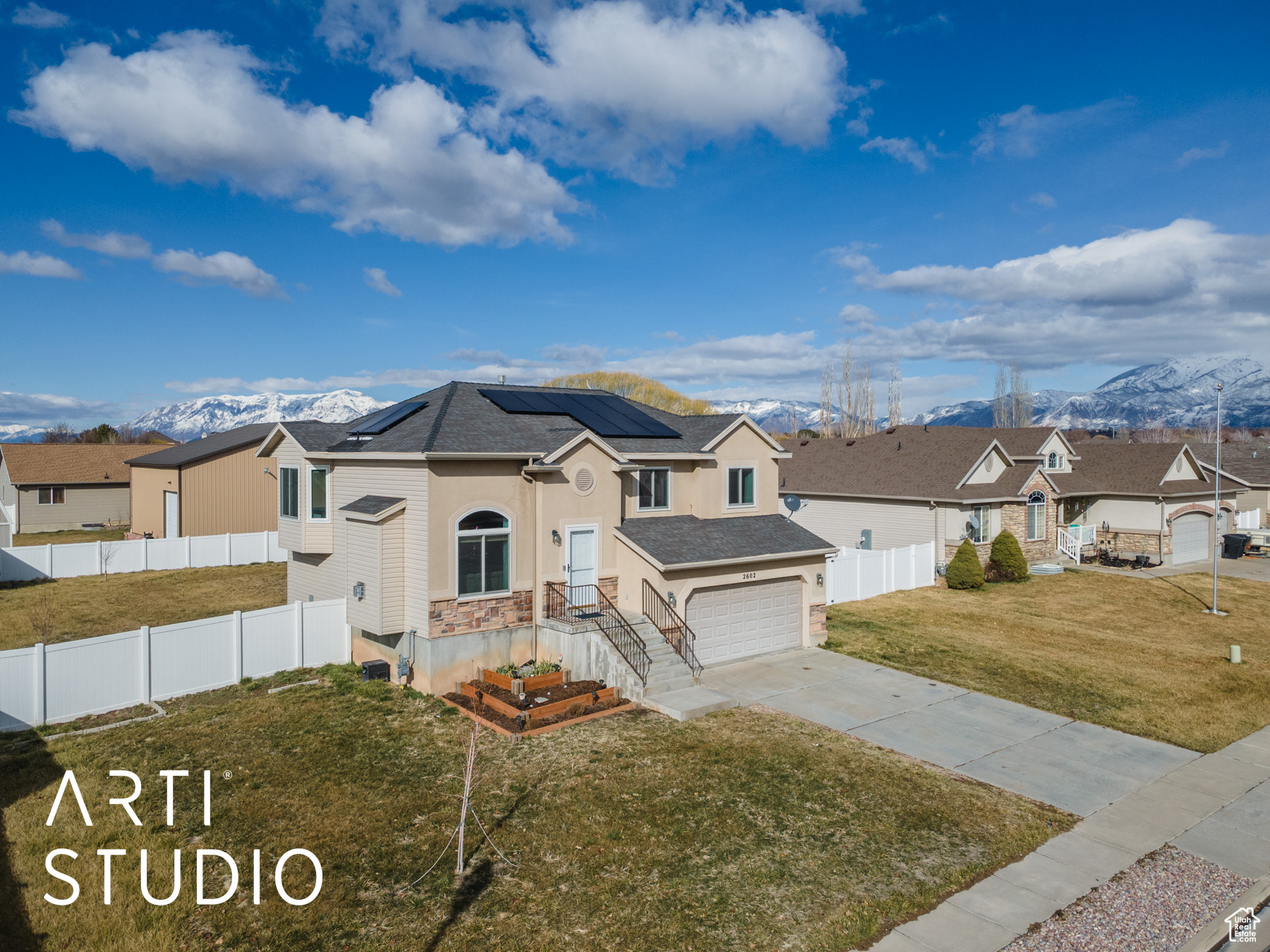 View of front of home featuring roof mounted solar panels, fence, a mountain view, concrete driveway, and a front yard