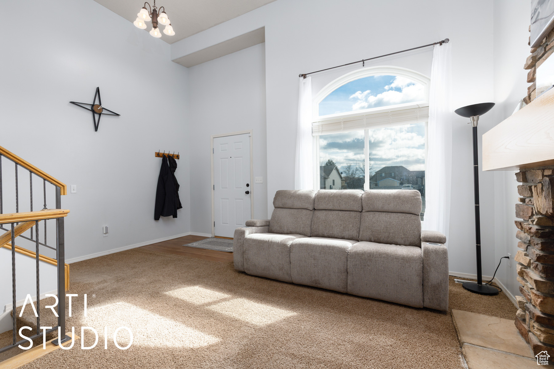 Living room featuring stairway, carpet, baseboards, a towering ceiling, and a notable chandelier