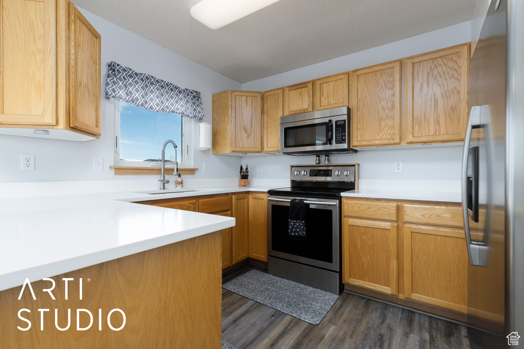 Kitchen featuring a sink, stainless steel appliances, dark wood finished floors, and light countertops