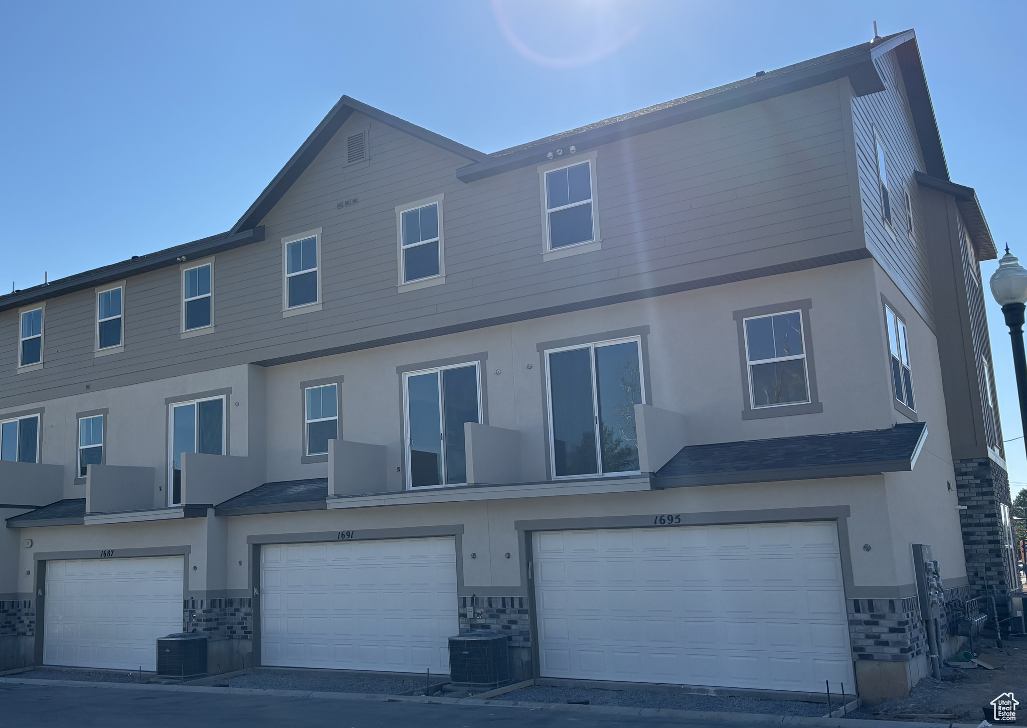 Back of property with stucco siding, stone siding, and an attached garage