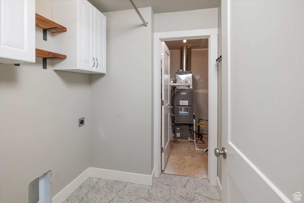 Clothes washing area with marble finish floor, heating unit, cabinet space, baseboards, and hookup for an electric dryer