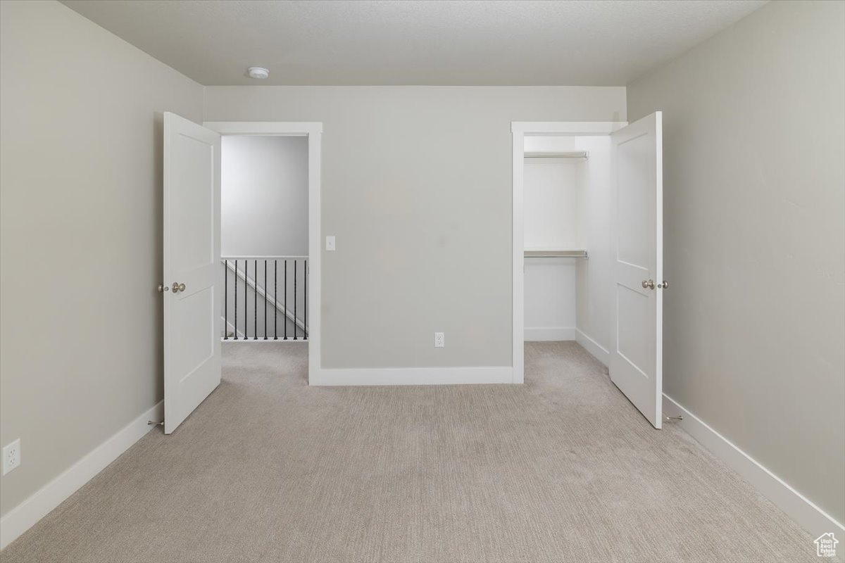 Unfurnished bedroom featuring a walk in closet, baseboards, and carpet floors