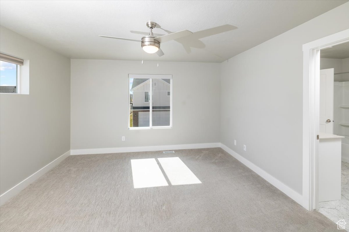 Unfurnished room with a ceiling fan, baseboards, and light carpet