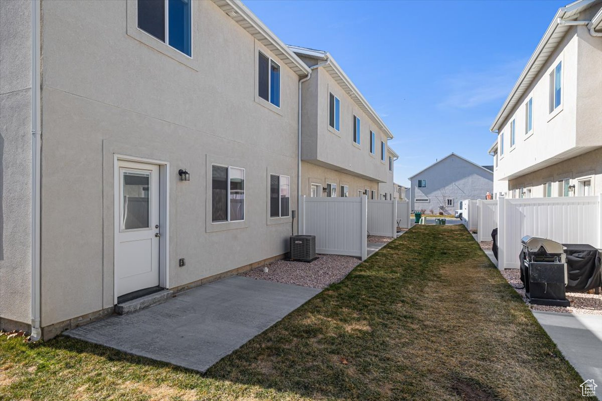 Exterior space featuring fence, a residential view, stucco siding, a lawn, and a patio area