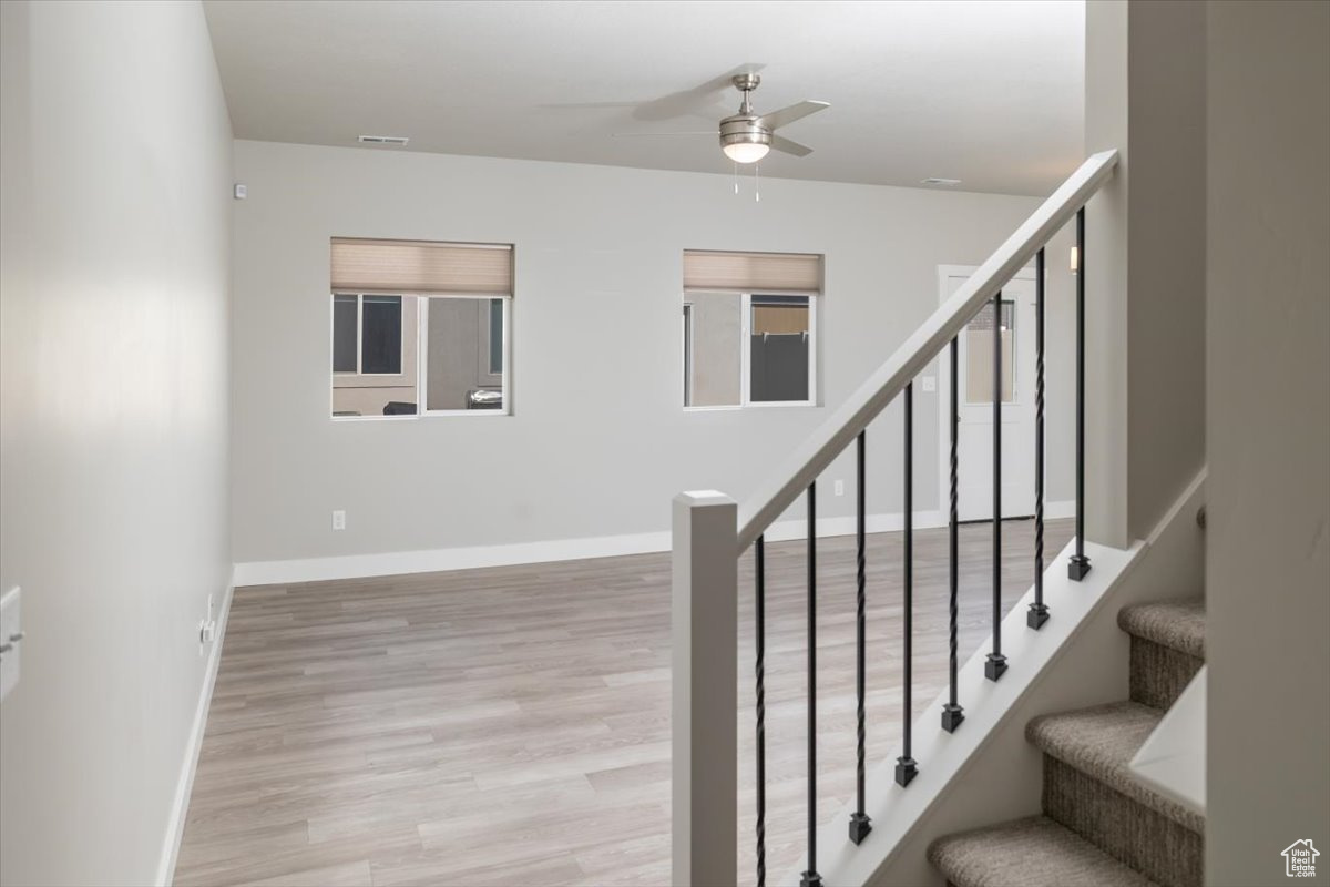 Stairs featuring a ceiling fan, wood finished floors, and baseboards