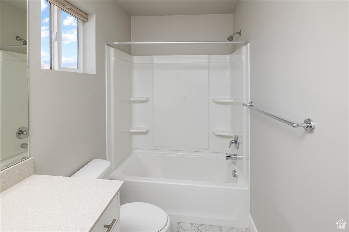 Bathroom featuring vanity, toilet, and washtub / shower combination