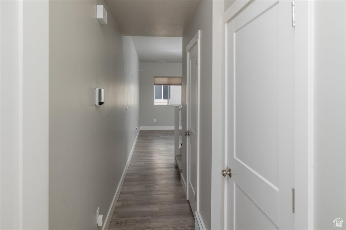 Hall with dark wood-type flooring and baseboards