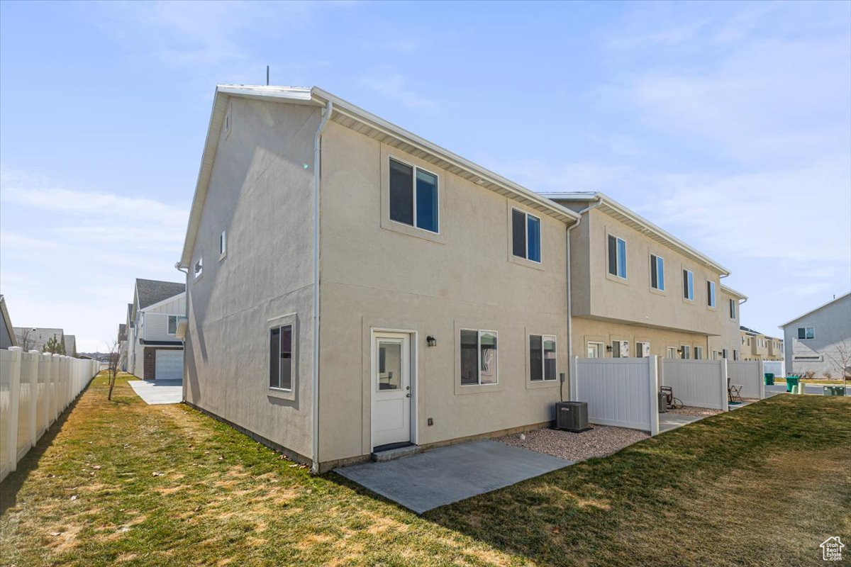 Back of house featuring a patio, a yard, fence, and stucco siding