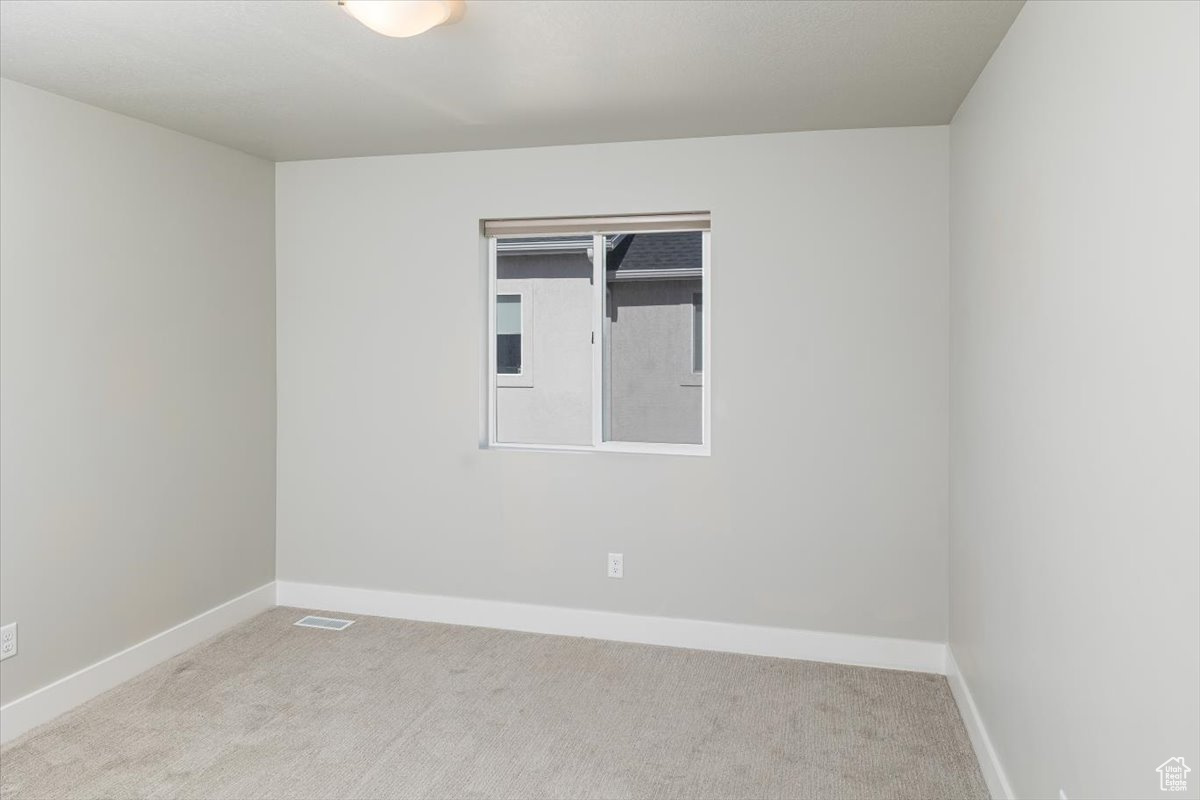 Carpeted spare room with baseboards and visible vents