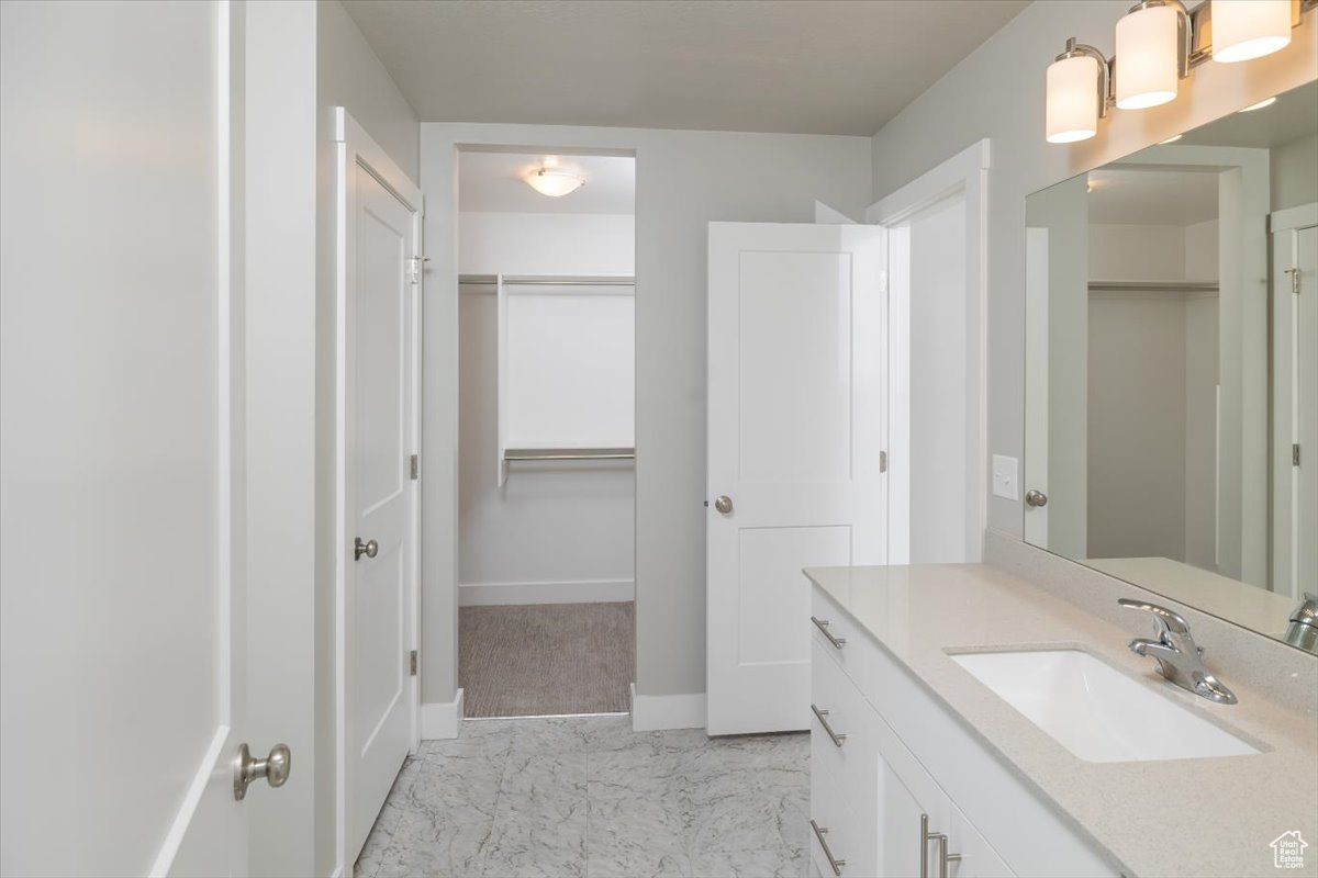 Bathroom with baseboards, vanity, marble finish floor, and a spacious closet