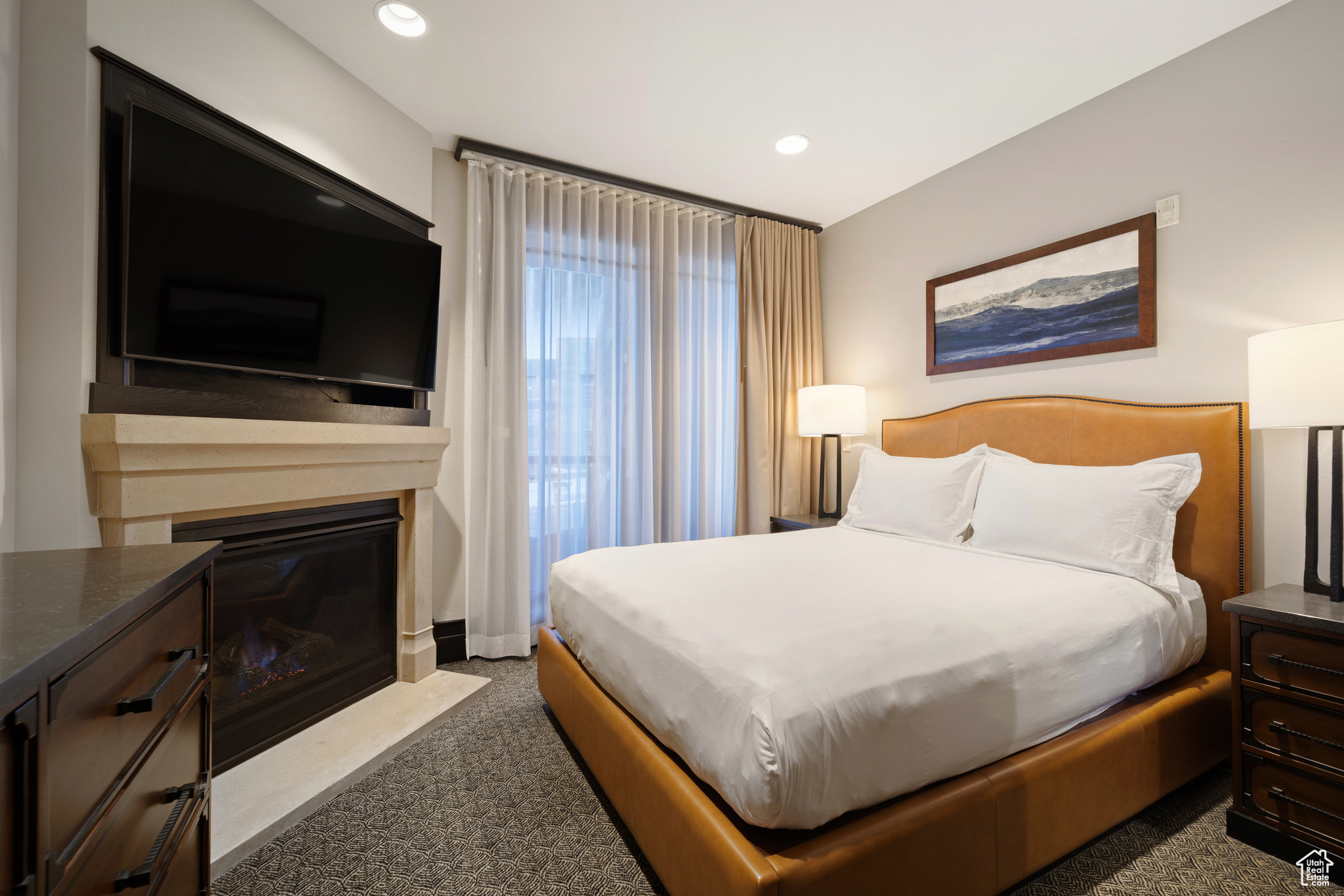 Bedroom featuring dark colored carpet, a fireplace with flush hearth, and recessed lighting