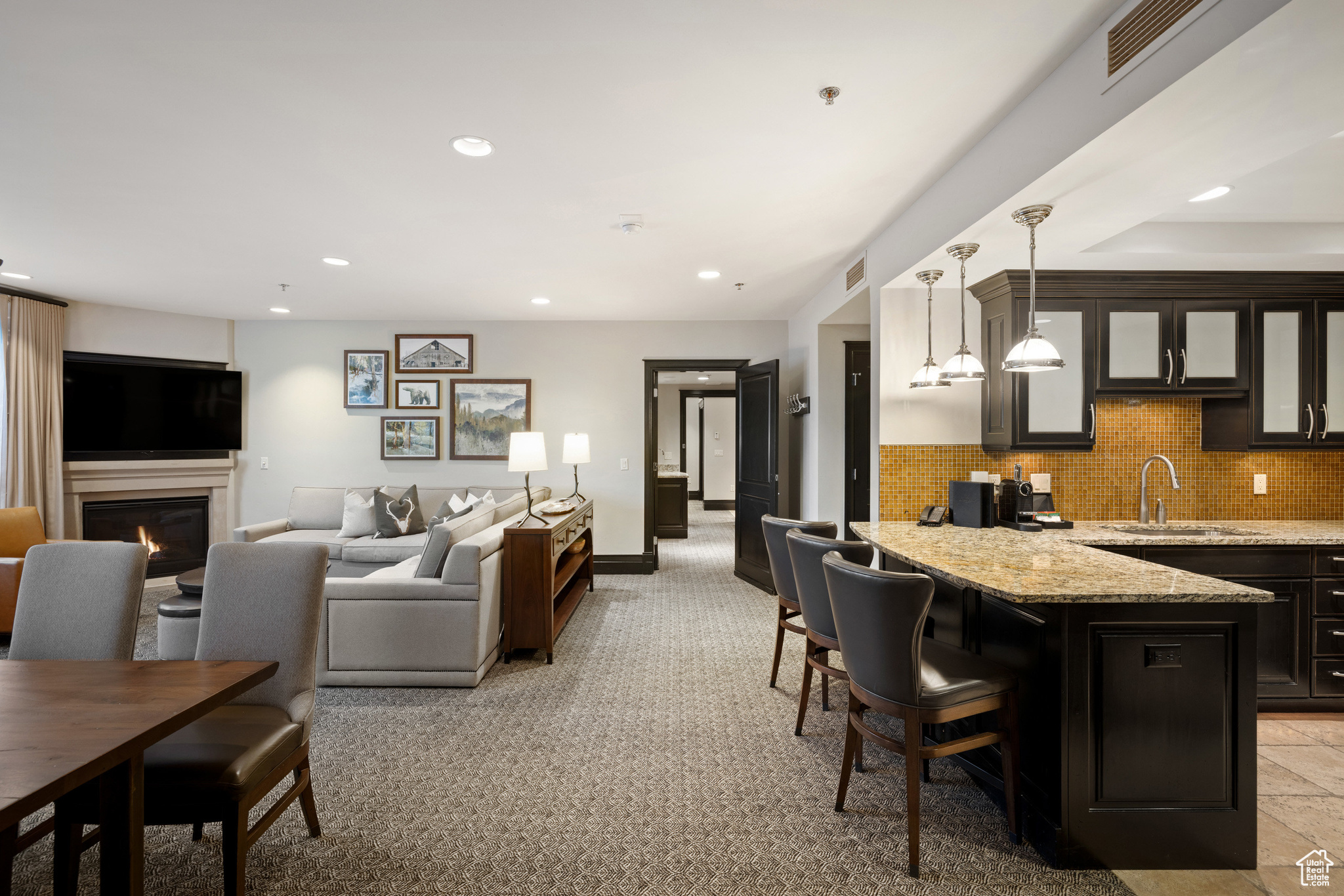 Interior space featuring recessed lighting, visible vents, a warm lit fireplace, and light carpet