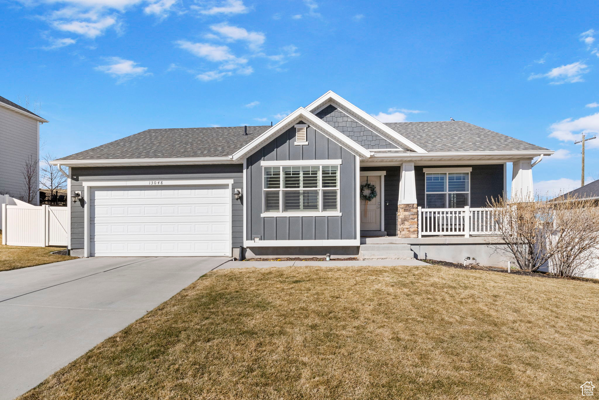 View of front of property with board and batten siding, fence, a front yard, a garage, and driveway