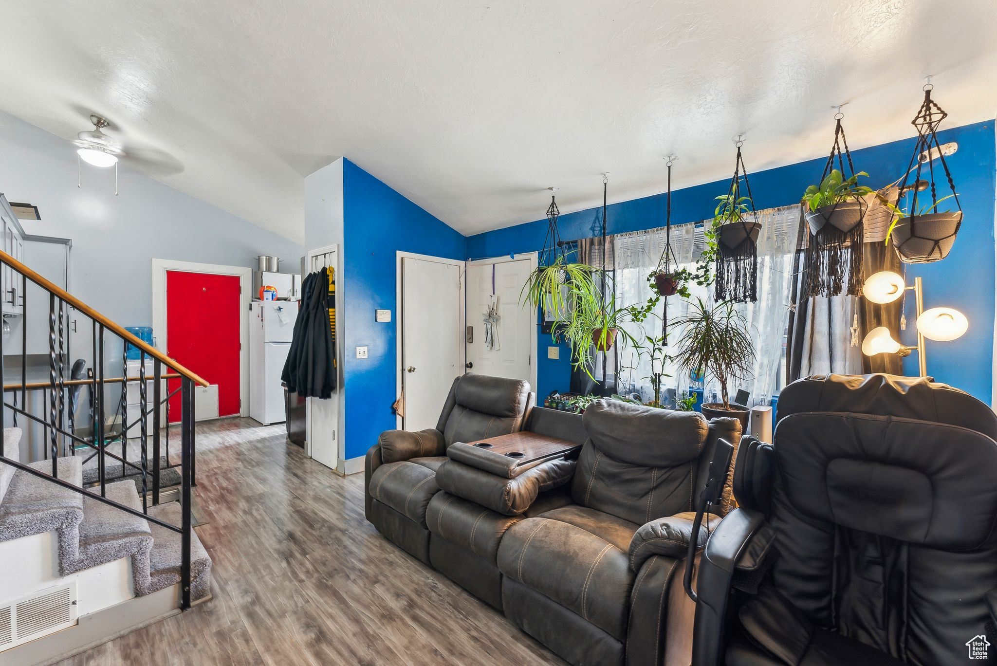 Living room with visible vents, stairway, vaulted ceiling, wood finished floors, and a ceiling fan