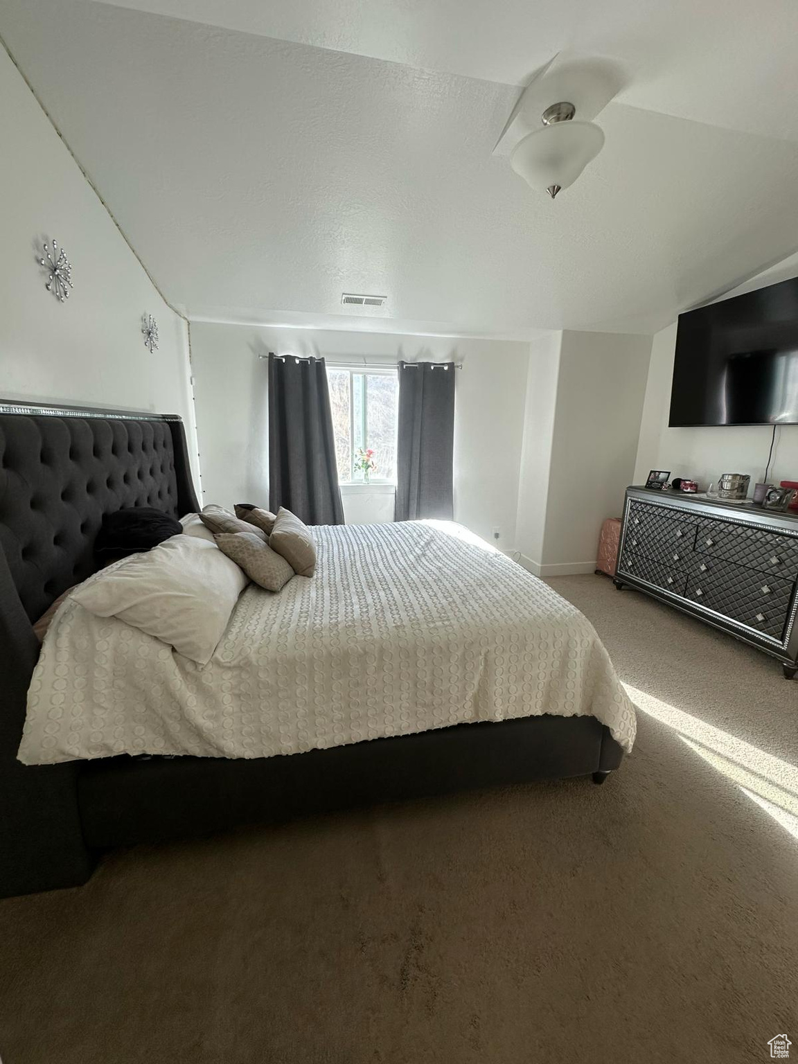 Bedroom featuring lofted ceiling, carpet, visible vents, and baseboards