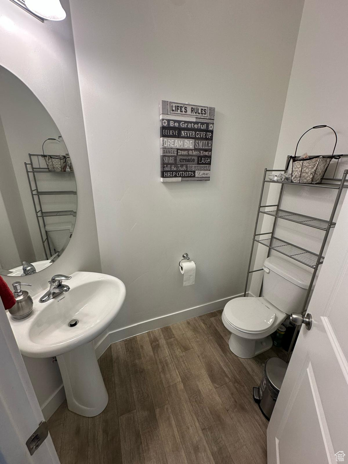 Half bathroom featuring wood finished floors, toilet, and baseboards