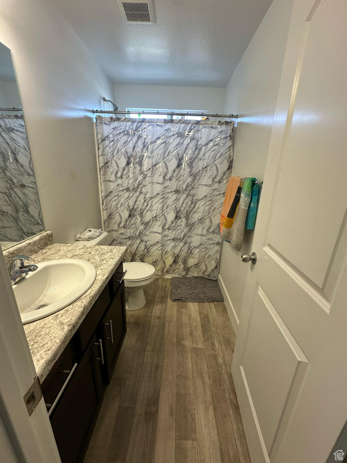 Full bathroom featuring visible vents, toilet, a shower with curtain, wood finished floors, and vanity
