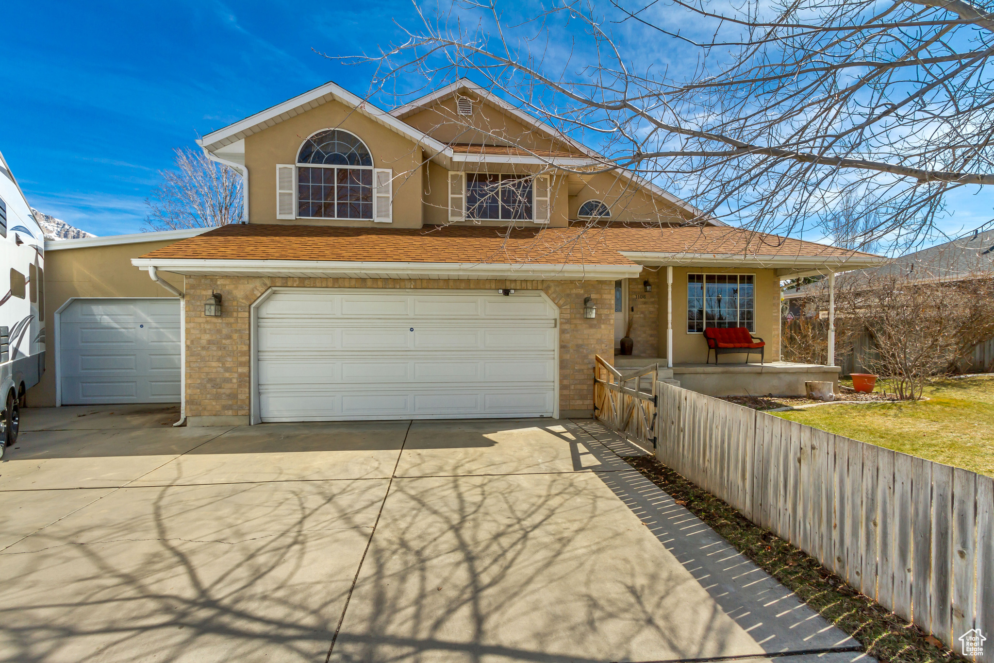 View of front of home with stucco siding, brick siding, a garage, and driveway