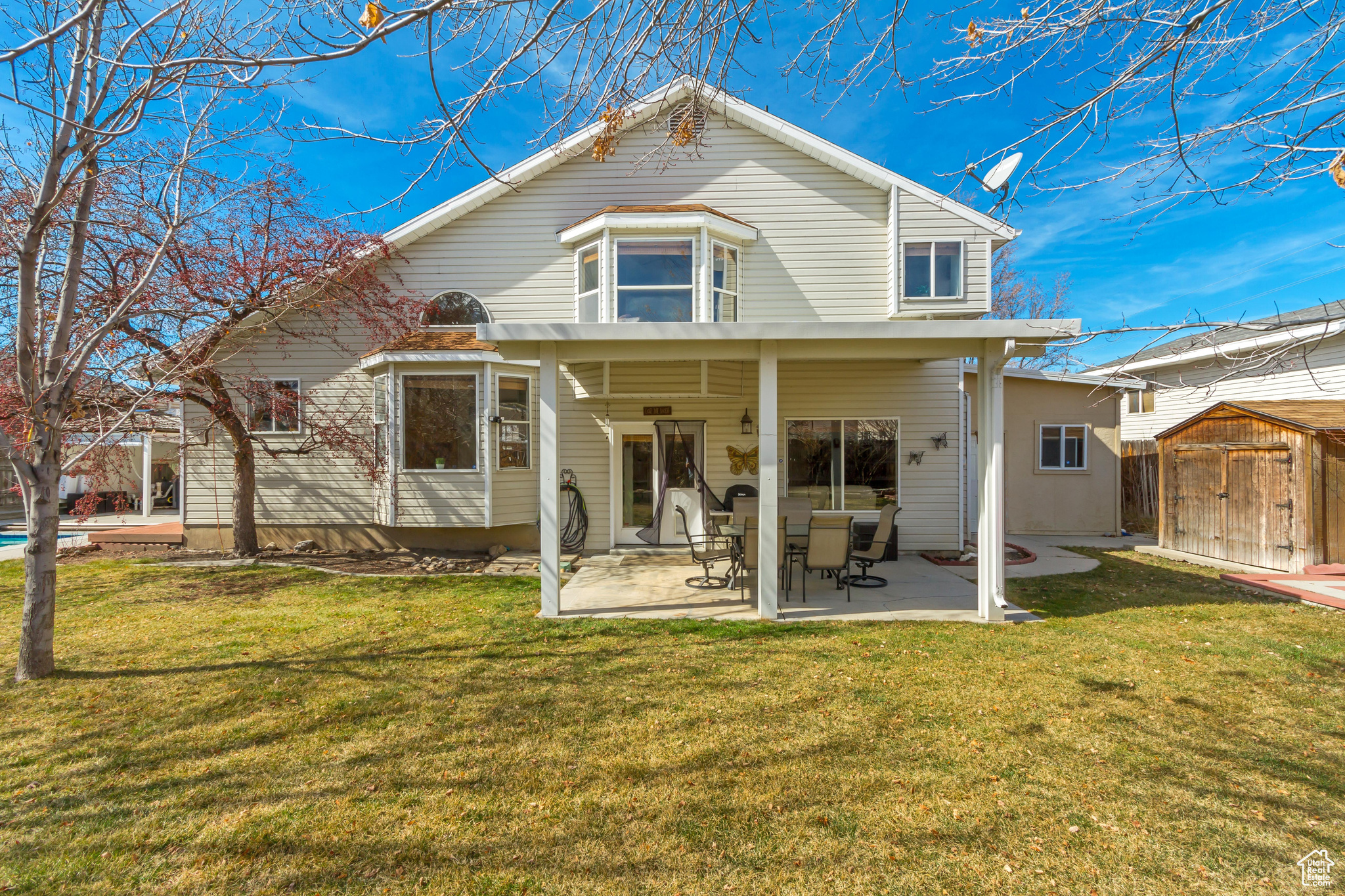 Back of house featuring a patio area, a lawn, a storage unit, and an outdoor structure