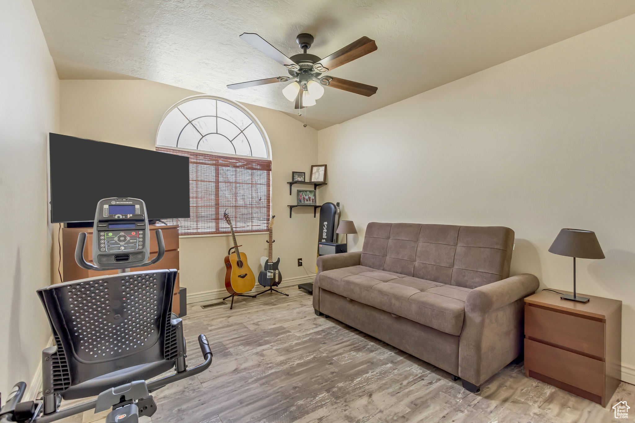Interior space featuring a ceiling fan, vaulted ceiling, wood finished floors, and baseboards