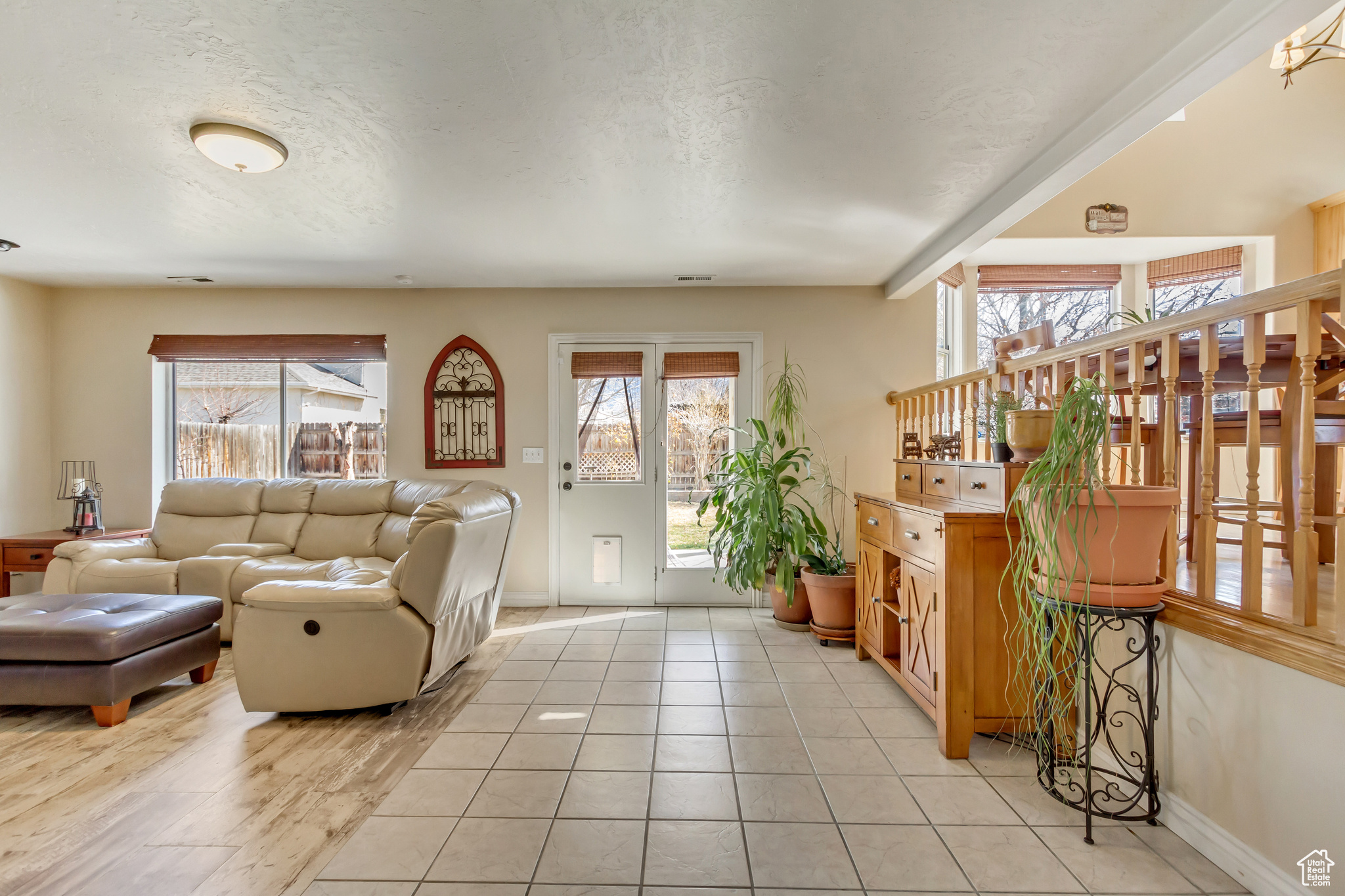 Living area with light tile patterned floors, visible vents, a textured ceiling, and baseboards