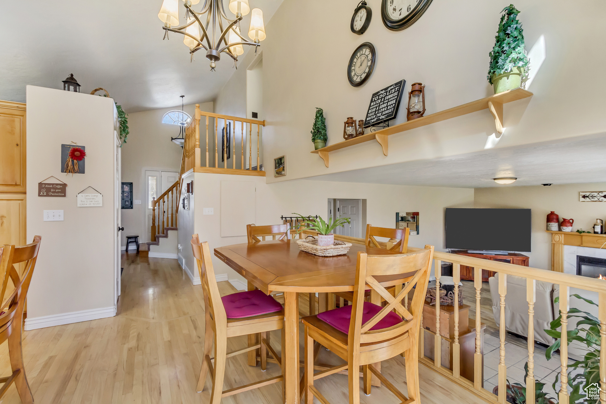 Dining area featuring baseboards, stairs, a fireplace, light wood-style floors, and high vaulted ceiling