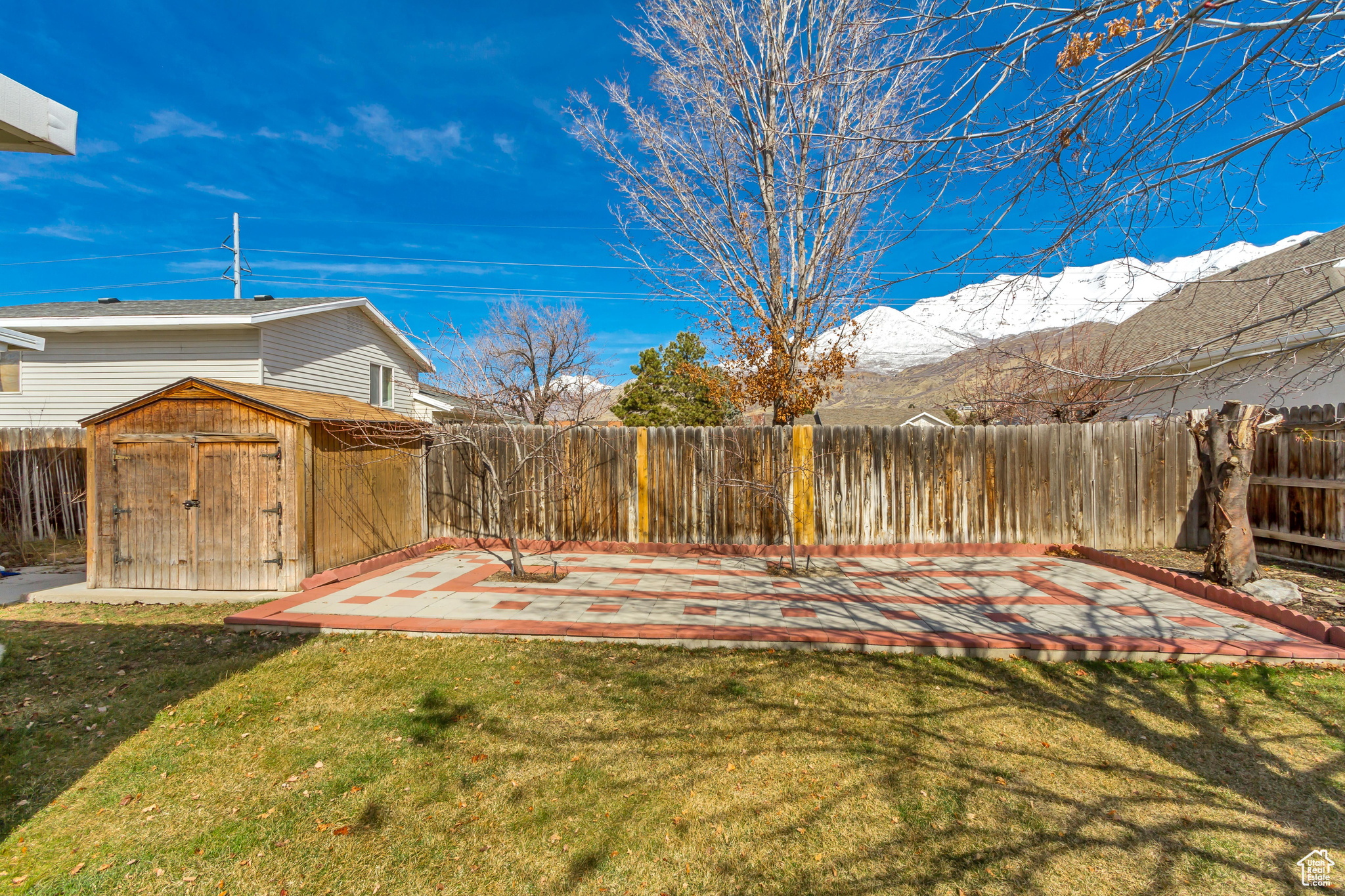 View of yard with a patio, a fenced backyard, an outdoor structure, a storage unit, and a mountain view