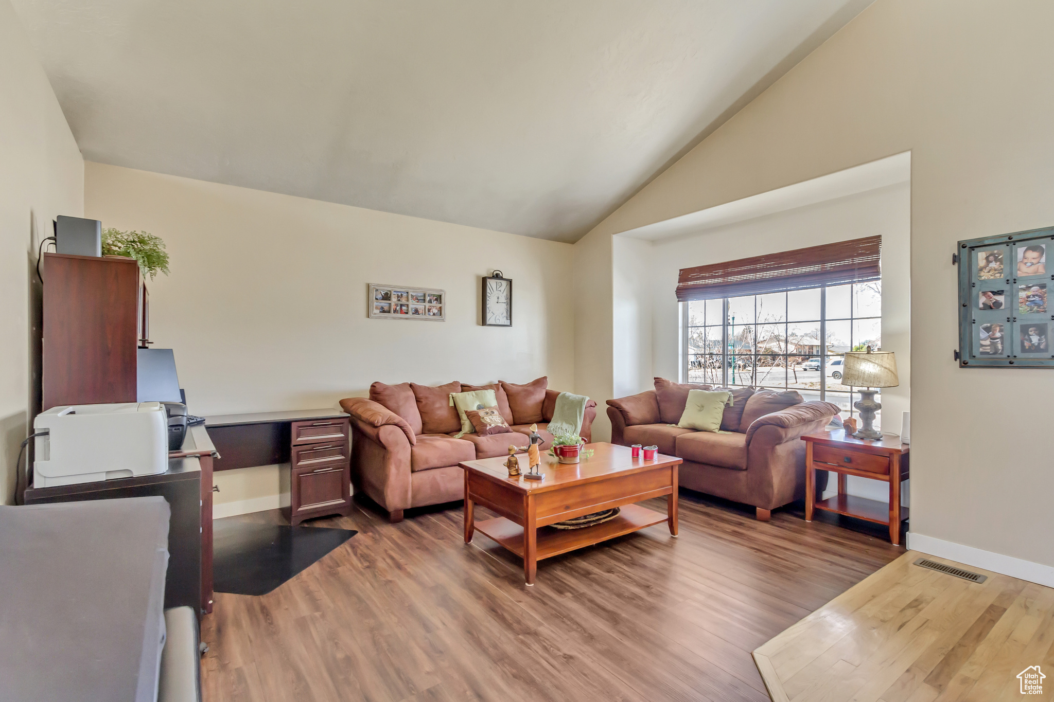 Living room featuring visible vents, baseboards, light wood-style floors, and vaulted ceiling